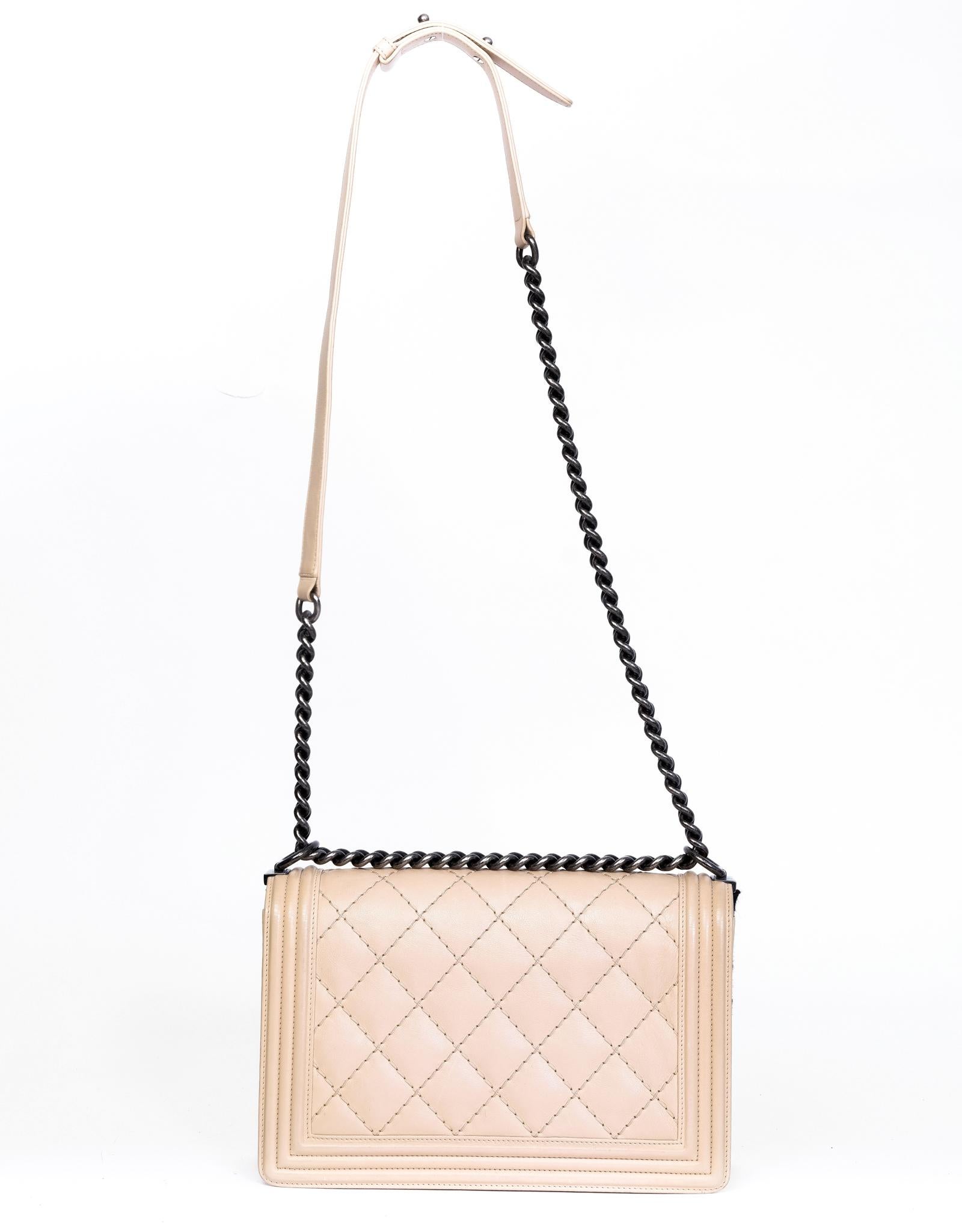 This Chanel Boy Bag in nude is constructed with sleek lines in a rectangular shape with diamond quilted leather exterior. Featuring gun metal toned hardware with an interlocking CC Chanel logo, a large link chain, a leather cross body strap, and
