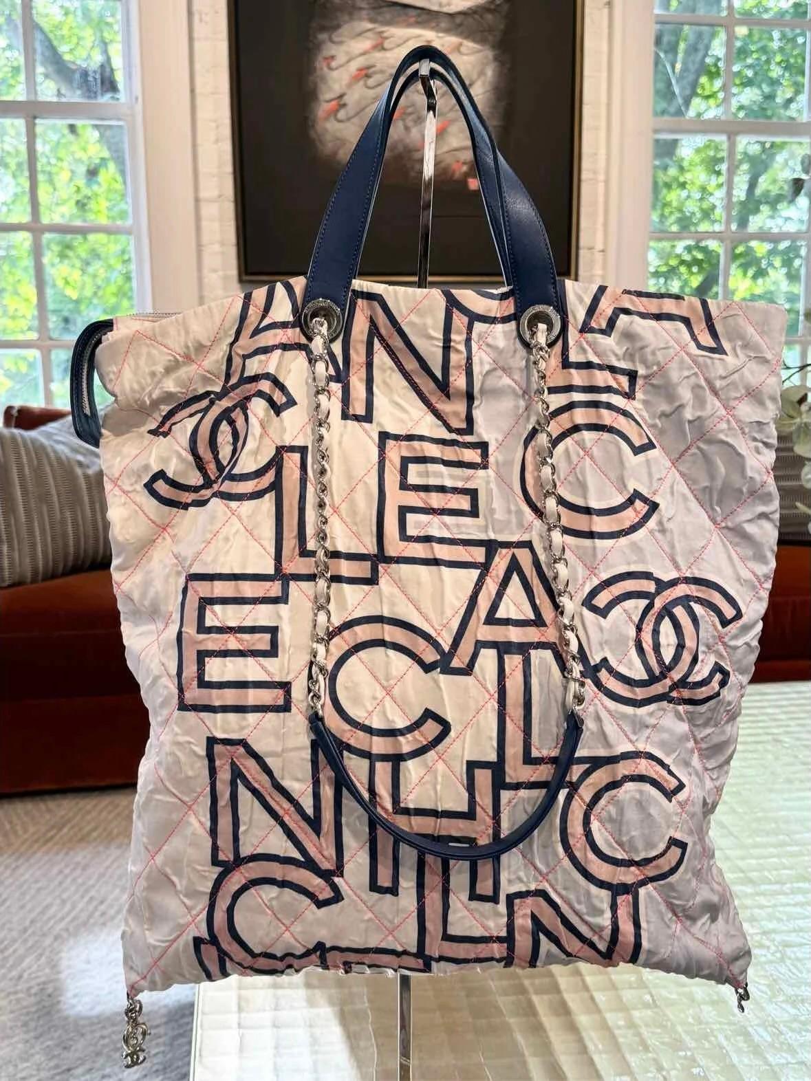 This Chanel nylon CC logo printed bag features white, pink, and blue diamond stitching in an intricate design. The bag features a blue leather top handle and a front zipper pocket, and fabric adjustable shoulder straps. The main zipper opens to a