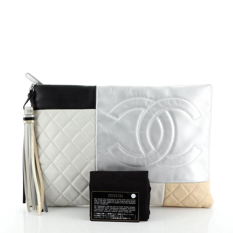 This Chanel O Case Clutch Colorblock Quilted Leather Large, crafted from neutral and multicolor quilted leather, features a CC logo on the front and silver-tone hardware. Its zip closure opens to a gray nylon interior. Hologram sticker reads: