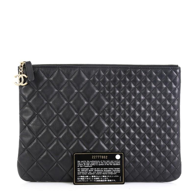 This Chanel O Case Clutch Quilted Lambskin Medium, crafted from black quilted lambskin leather, features a tiny CC logo on the front and gold-tone hardware. Its zip closure opens to a black nylon and fabric interior with zip pocket. Hologram sticker