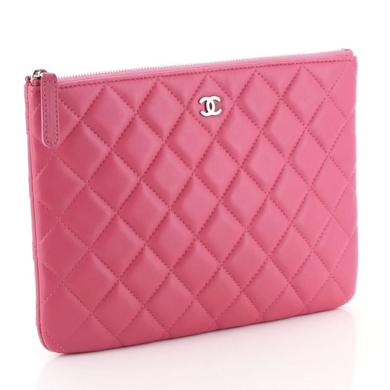 This Chanel O Case Clutch Quilted Lambskin Small, crafted from pink quilted lambskin leather, features a tiny CC logo on front and silver-tone hardware. Its zip closure opens to a pink fabric interior. Hologram sticker reads: 19519442. 

Condition: