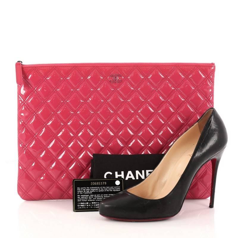 This authentic Chanel O Case Clutch Quilted Patent Large adds a touch of elegance to your everyday outfits. Crafted from pink quilted patent leather, this clutch features tiny CC logo on the front and silver-tone hardware accents. Its zip closure