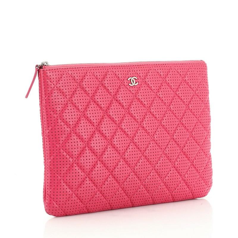 This Chanel O Case Clutch Quilted Perforated Lambskin Medium, crafted from pink quilted perforated lambskin, features a tiny CC logo on the front and gunmetal-tone hardware. Its zip closure opens to a pink nylon interior. Hologram sticker reads: