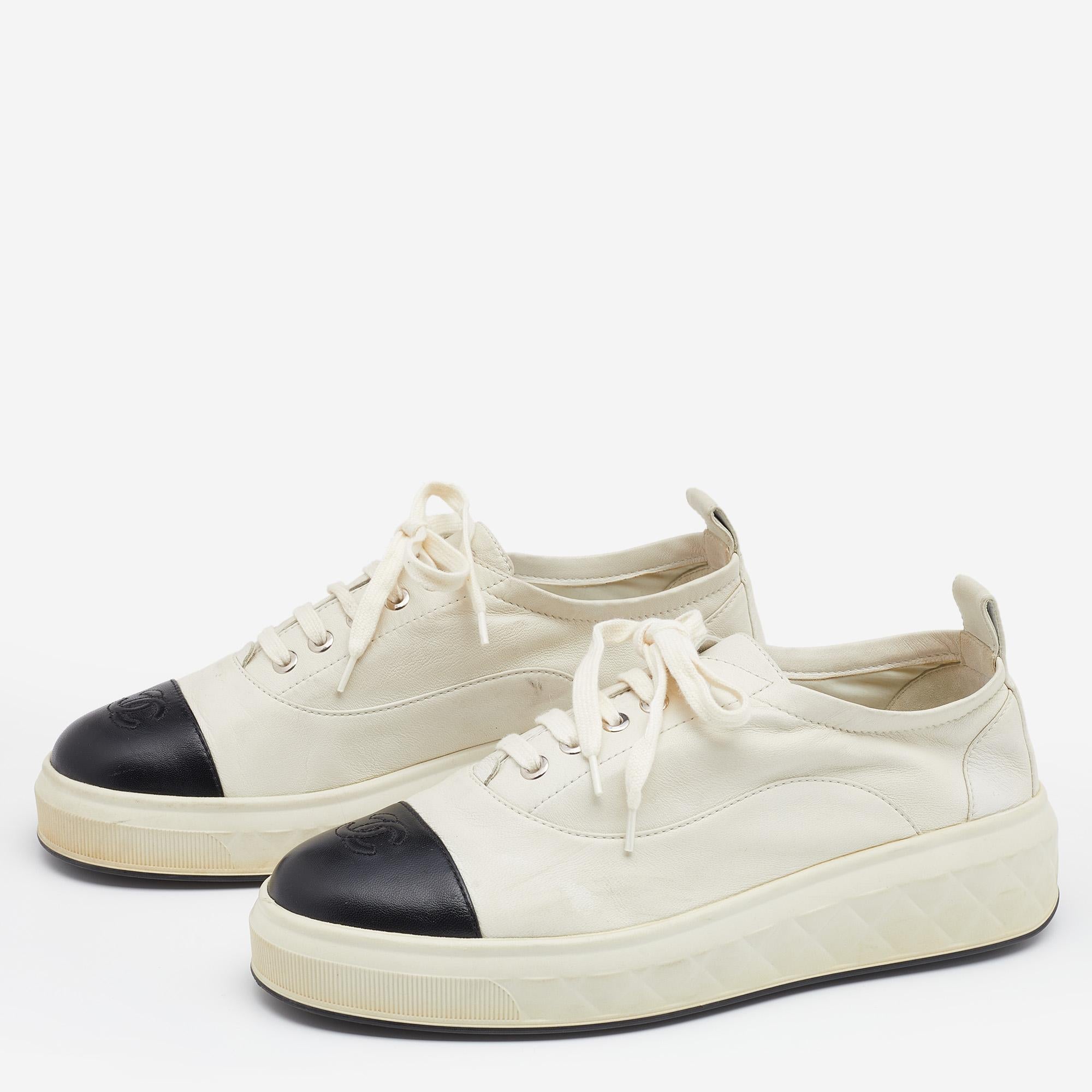 These Oxford sneakers from the House of Chanel are here to grant your feet the ultimate comfortable experience. They are crafted from off-white and black leather and flaunt lace-up fastenings, silver-tone hardware, and cap toes. Add these trendy