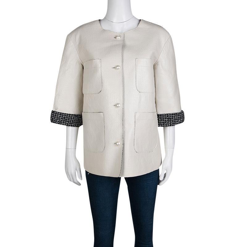 This evening jacket from Chanel in an off-white tone is a must have piece in your closet. Crafted out of lambskin leather and lined with soft wool blends, this jacket has a contrast lined design. The pearl buttons further enhance the look of this