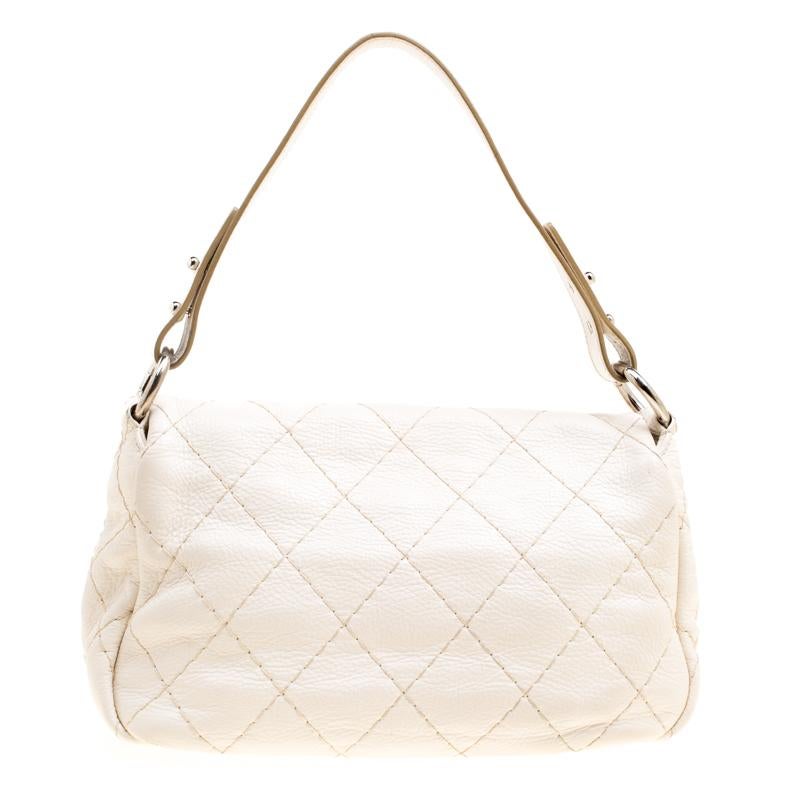 Unmistakably designed in Italy from Chanel’s signature quilted leather in an off-white hue, this On the Road flap bag presents a chic touch to one’s evening silhouette. Adorned with a flat shoulder strap, the outer flap is secured with a turn lock