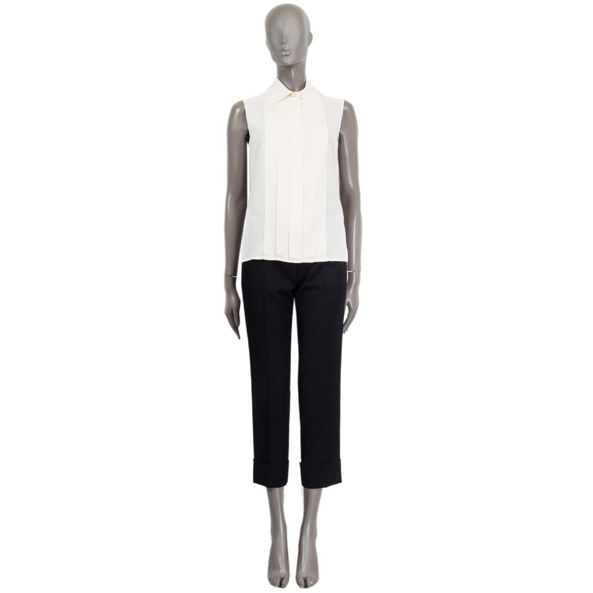 100% authentic Chanel sleeveless blouse in off-white silk (100%) with pleated front and flat collar. The blouse closes with six hidden 'Chanel Paris' buttons and one visible pearl CC button. Has been worn and is in excellent