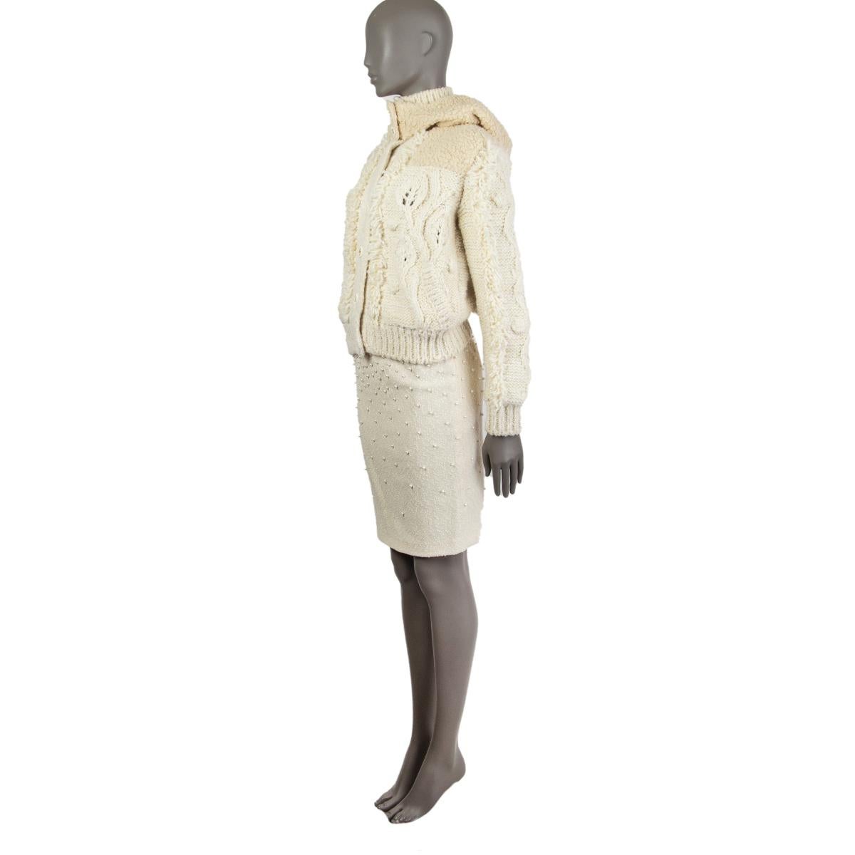 Chanel knitted fringe bomber in off-white wool (57%), cashmere (40%) and silk (3%). Come with a detachable hood in off-white camel hair (87%) and silk (13%). Closes on the front with buttons. Hood is lined in silk (100%). Has been worn and is in