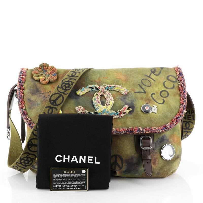 This Chanel On The Pavements Graffiti Messenger Bag Canvas Large, crafted from green canvas with multicolor graffiti and spray-painted design, features CC logo in boucle tweeds, decorative pins and buckle details, crossbody strap, and aged