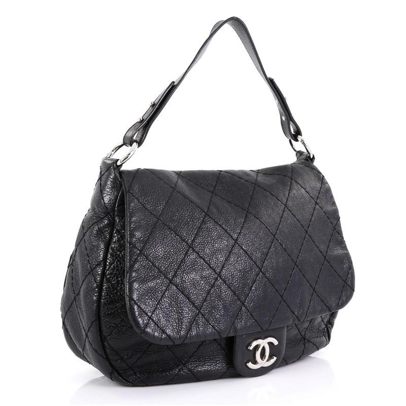 This Chanel On the Road Flap Bag Quilted Leather Large, crafted from black quilted leather, features CC logo at its frontal flap, flat leather shoulder strap with links and silver-tone hardware. Its magnetic snap closure opens to a black satin