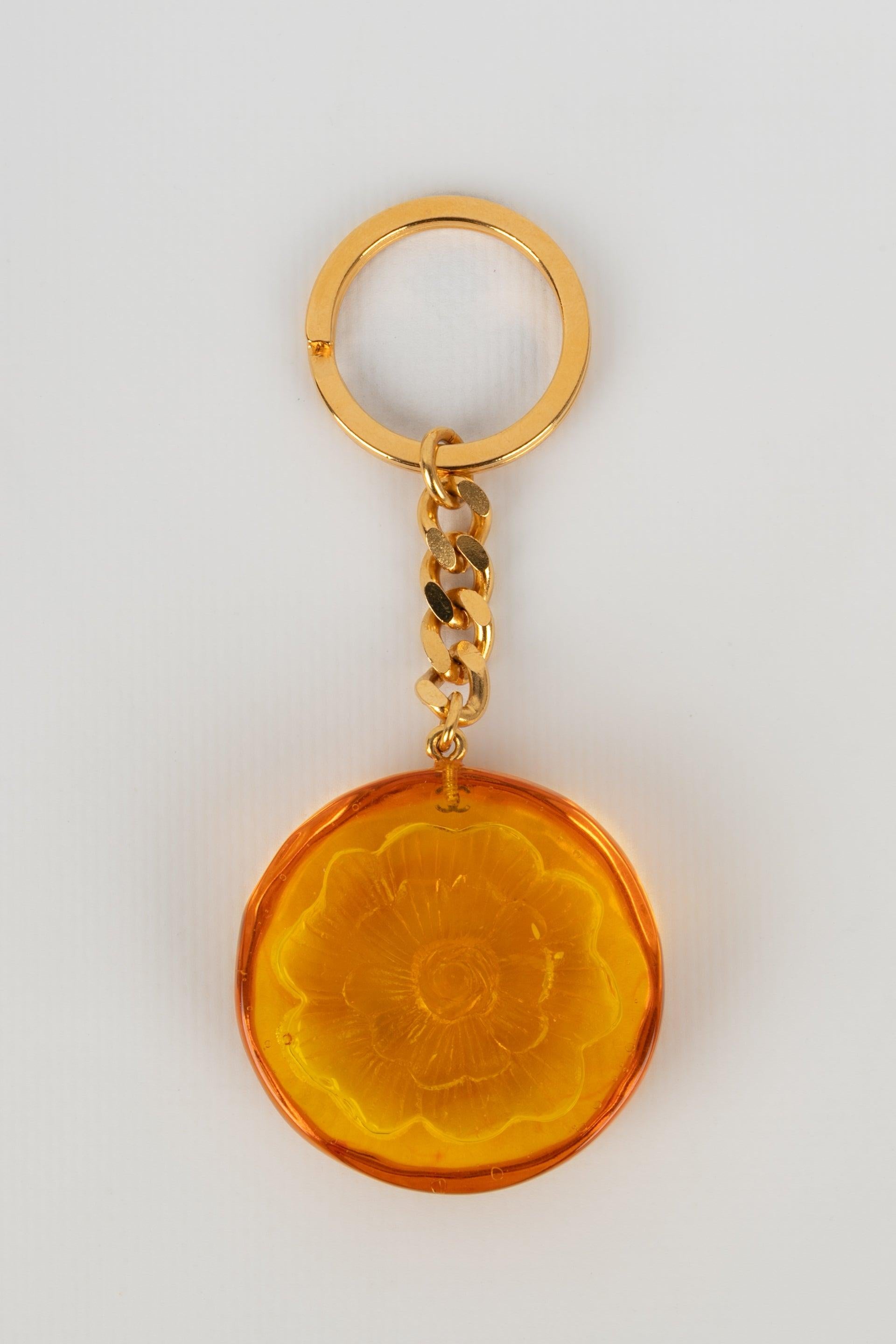 Chanel - Schlüsselanhänger aus goldenem Metall und orangefarbenem Bakelit mit einer Kameliendarstellung.

Zusätzliche Informationen:
Zustand: Sehr guter Zustand
Abmessungen: Höhe: 11 cm

Sellers Referenz: BRB149