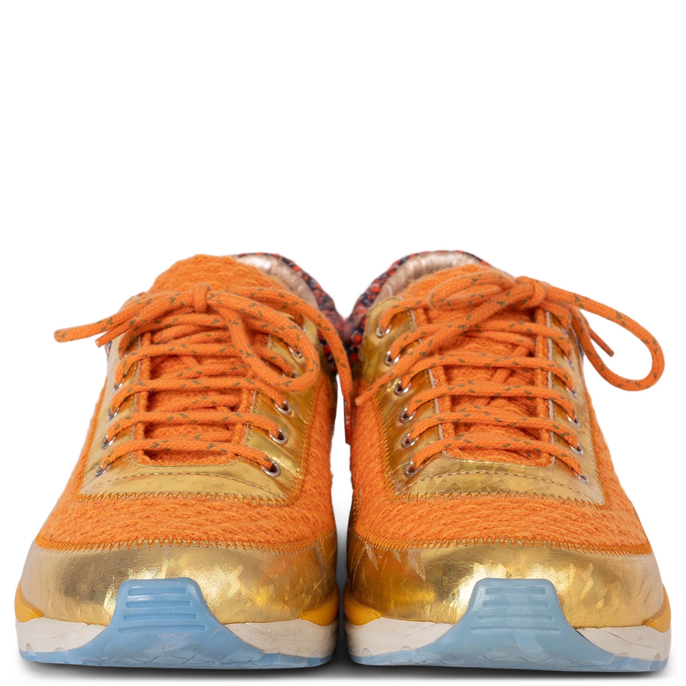 Ces baskets basses 100% authentiques de Chanel associent des textures ludiques à des accents audacieux. Confectionnées en tweed orange, elles sont ornées de bordures en PVC holographique doré, de daim brique et de détails en tweed bleu marine et