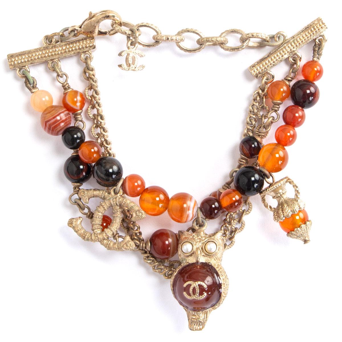 authentic Chanel Paris - Greece bracelet in rust, orange, burgundy and honey colored faux stones embellished with CC logo and an owl in light-gold metal. Has been worn and is in excellent condition. 

Width 7cm (2.7in)
Length 22cm (8.6in)
Hardware