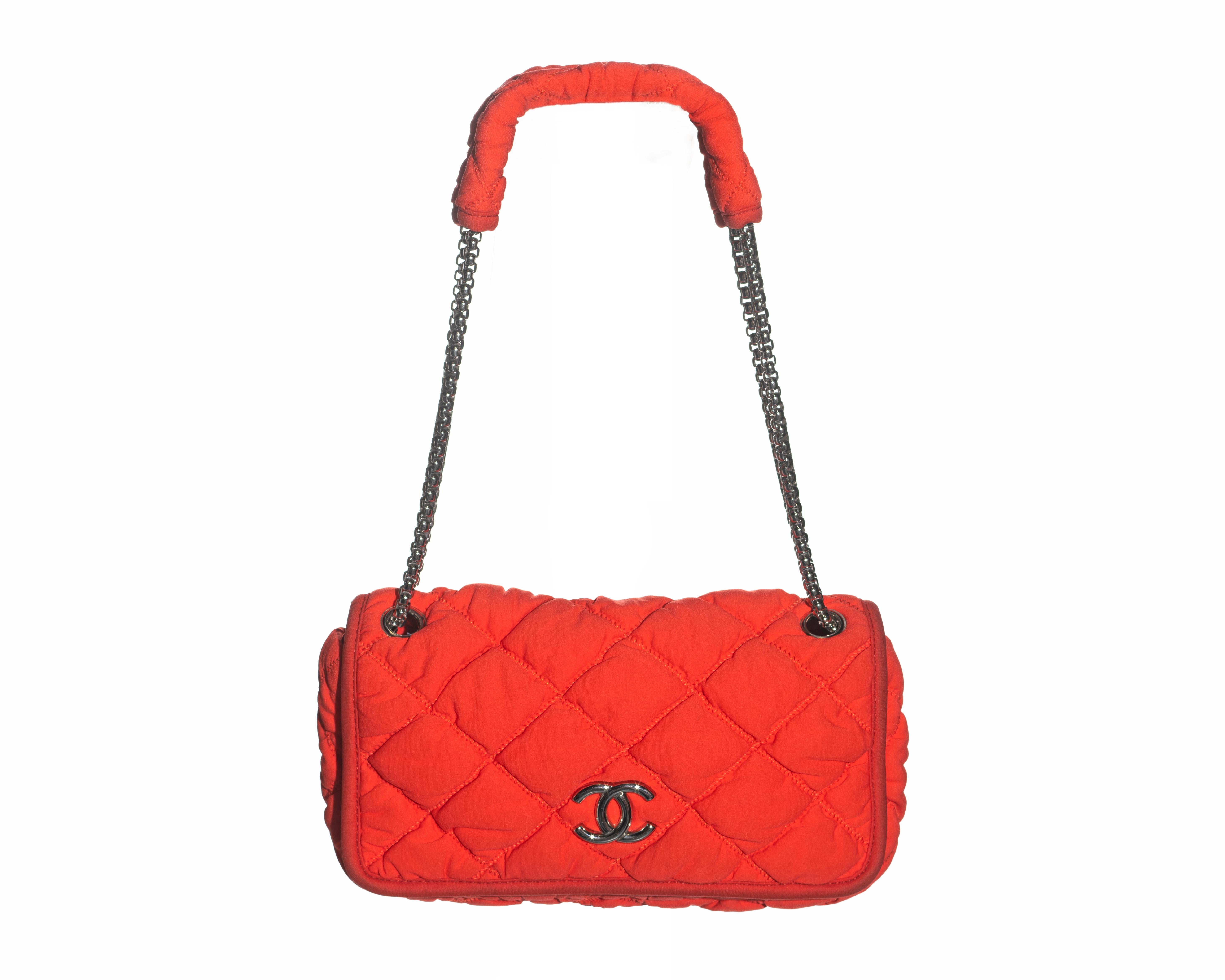 ▪ Chanel orange nylon flap bag 
▪ Bubble quilted 
▪ Silver 'Reissue' chain shoulder strap 
▪ CC logo clasp with magnetic closure 
▪ Silver satin lining 
▪ Comes with authenticity card
▪ c. 2008 - 2009
▪ Made in Italy