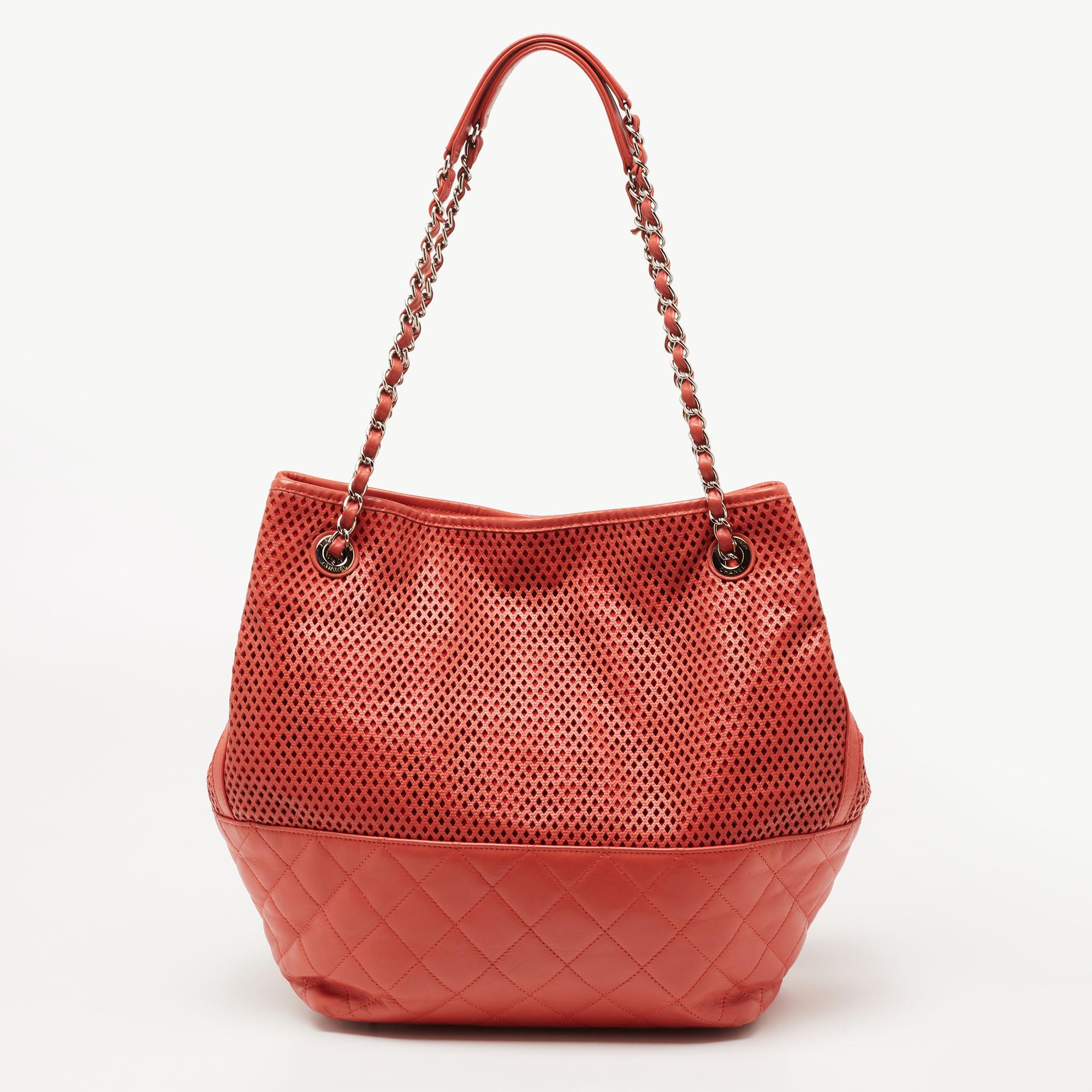 Emanating luxe vibes and gracefulness with its creative design, this Up In The Air tote from Chanel proves to be an eye-catching everyday accessory. It is crafted from orange perforated leather and features gold-tone hardware, chain straps, and a