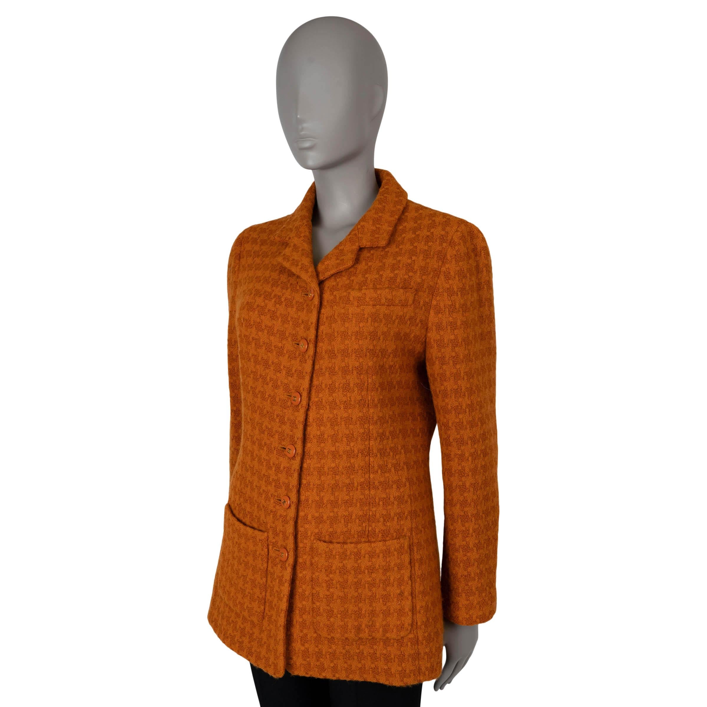 Diese 100% authentische Chanel Tweedjacke mit Hahnentrittmuster ist aus orangefarbener Wolle (99%) und Elastan (1%) gefertigt. Die taillierte Silhouette mit gekerbtem Revers, einer geschlitzten Brusttasche und zwei aufgesetzten Taschen auf der