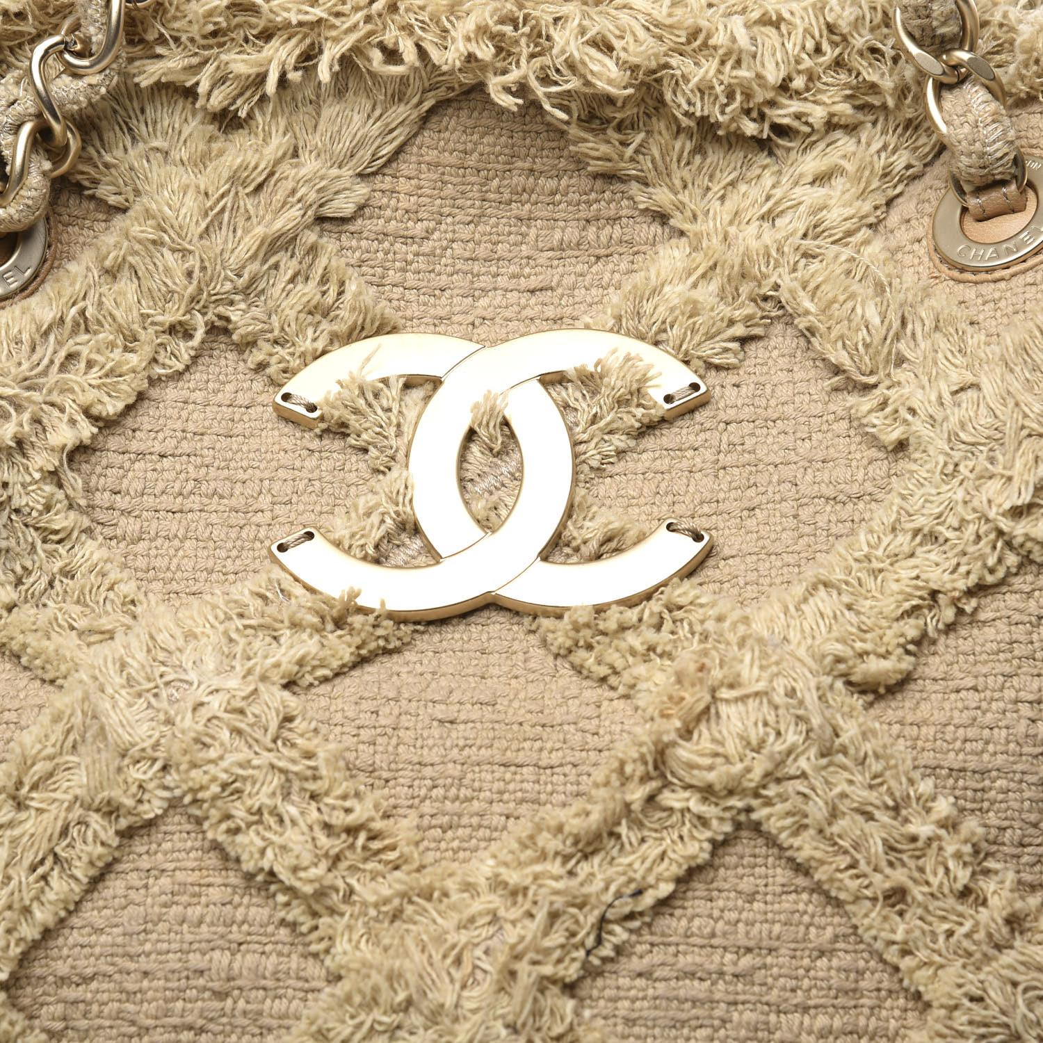 Este Chanel Nature Tote de tweed acolchado, confeccionado en tweed acolchado beige, presenta ribetes superiores acolchados con rombos, dos correas de cadena de piel entretejida, detalles de pliegues invertidos y herrajes dorados mate. Su cierre