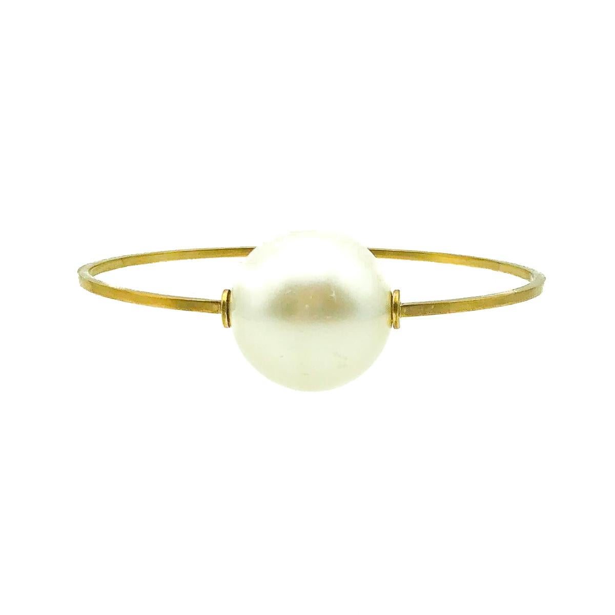 A Chanel Oversize Pearl Bangle. Crafted from lightly coloured gold plated metal and set with a whole faux pearl as the focal point. In very good vintage condition with only a few faint marks on the pearl and unnoticeable when worn, signed, approx.