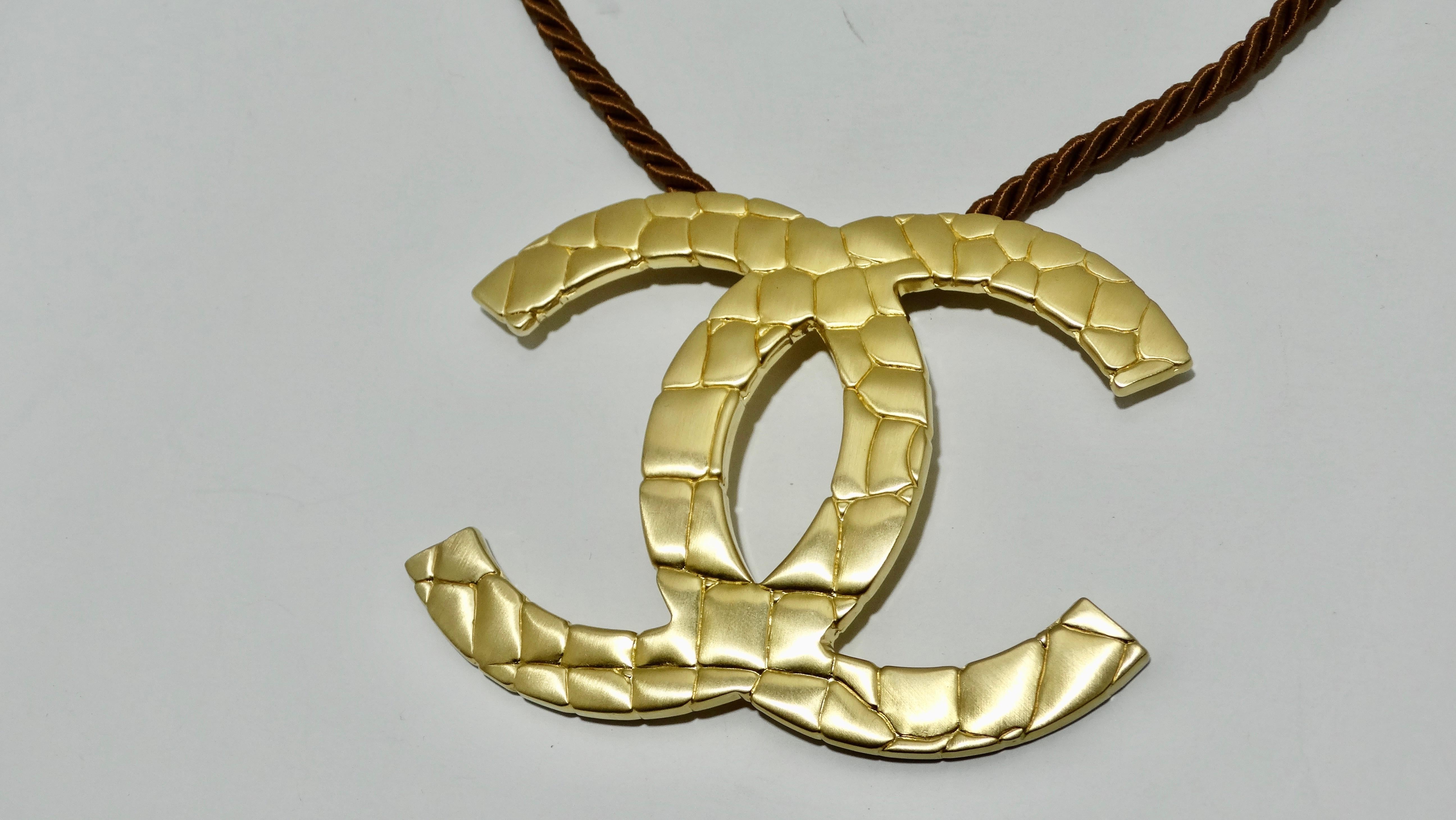 Its time to flaunt what you got with this fabulous Chanel Gold plated Oversized CC logo with a crocodile print pendant choker necklace from Chanel featuring a black torsade cotton and silk rope chain, a hook fastening and a large shiny silver plated
