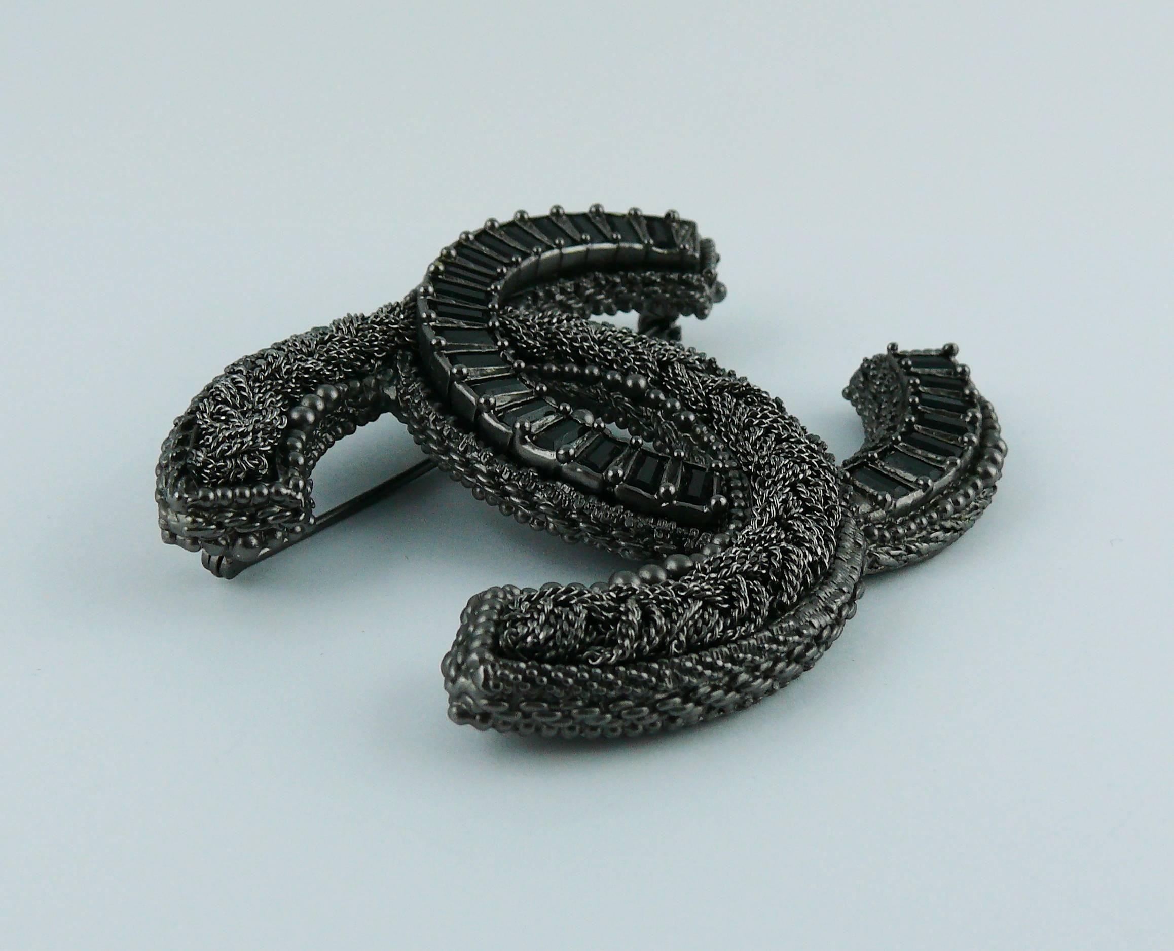 CHANEL oversized gunmetal patina CC logo brooch featuring a chain design and black baguette crystals.

2011 Collection.

Marked CHANEL A11 P Made in France.

Indicative measurements : max. height approx. 5.5 cm (2.17 inches) / width approx. 7.4 cm