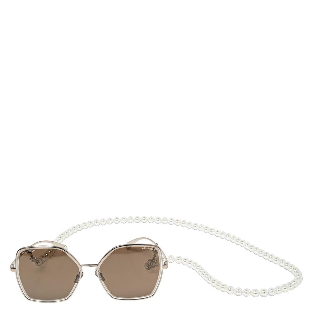 Aggiungi un tocco di classe al tuo look del giorno con questi occhiali da sole a farfalla di Chanel. Il design è incastonato in una montatura color oro, dotata di lenti di alta qualità con protezione UVA e UVB al 100%. Un filo di perle di vetro