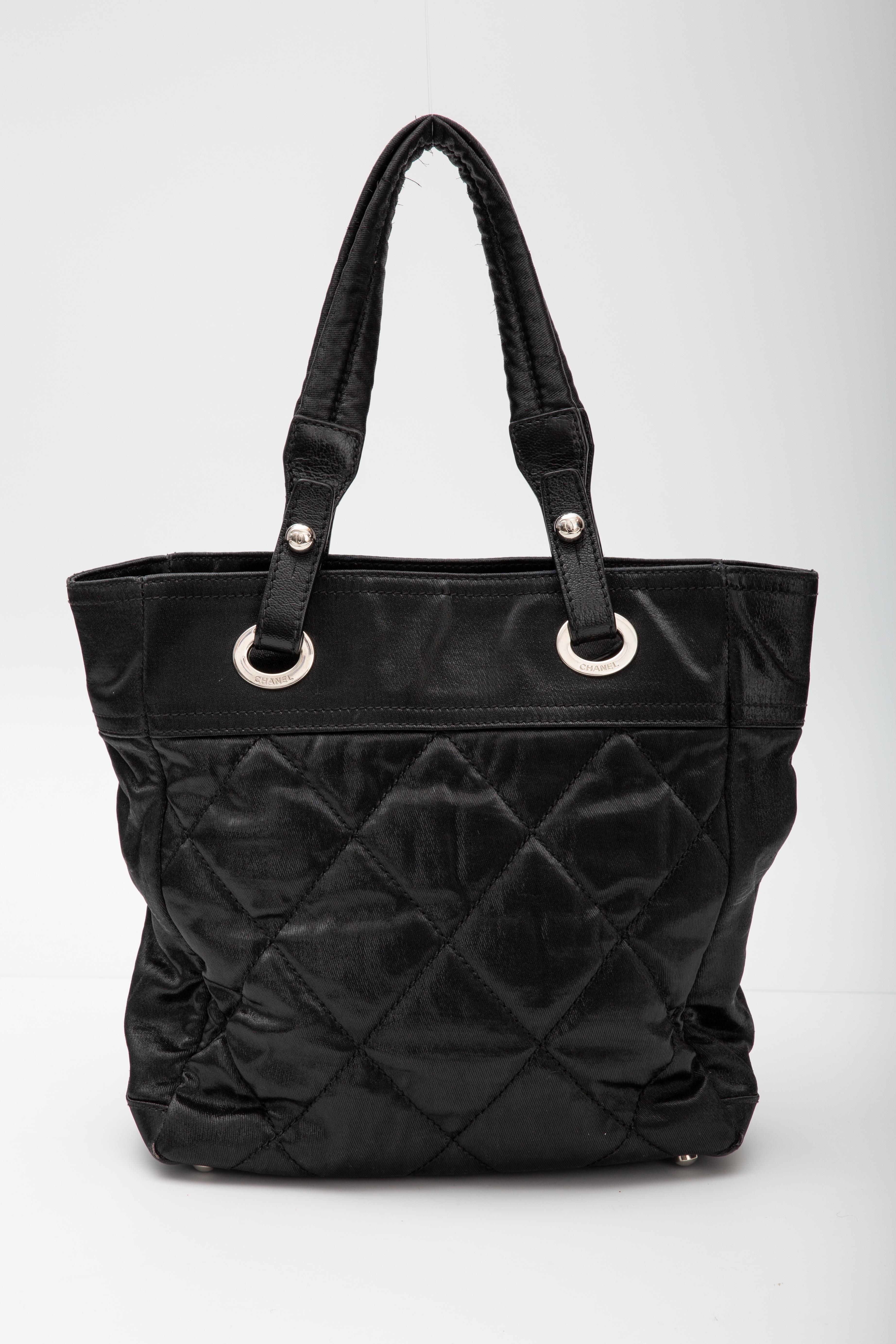This Chanel tote bag is made of quilted nylon and is from the Spring/Summer 2007 Collection by Karl Lagerfeld. The bag features an interlocking CC Logo charm, a quilted pattern, silver-tone hardware, dual shoulder straps, protective feet at base 