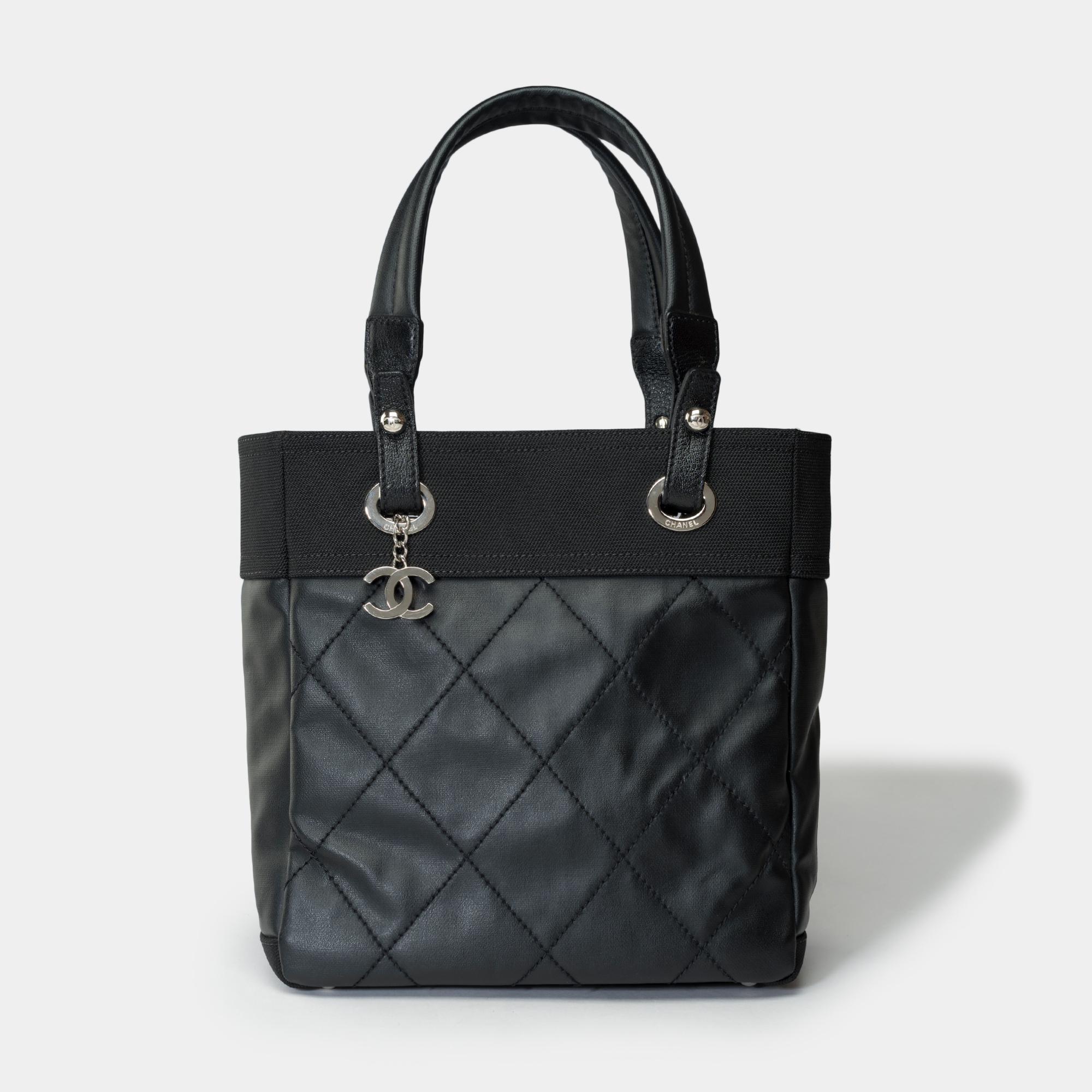 Elegant sac fourre-tout Chanel Paris-Biarritz en toile enduite noire et toile noire, garniture en métal argenté, double poignée en toile noire pour un portage à la main ou à l'épaule.

Une fermeture éclair
Doublure intérieure en toile noire, une