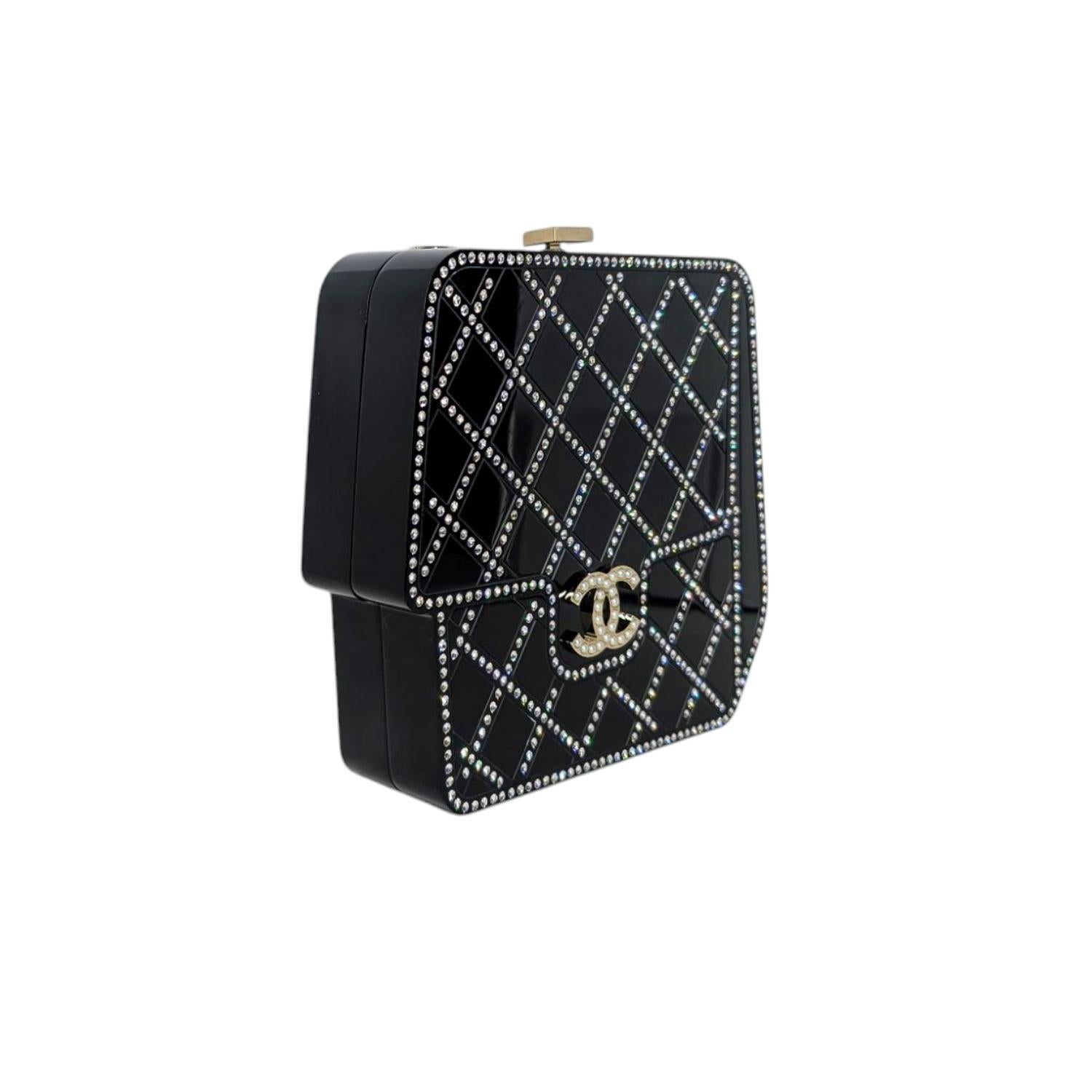 Questa giocosa pochette Chanel, che ricorda la Mini Square Classic Flap, presenta una tracolla a catena intrecciata e dettagli in perle. La trapuntatura nera mette in risalto le perle bianche e il logo CC dorato intarsiato di perle. Chiusura