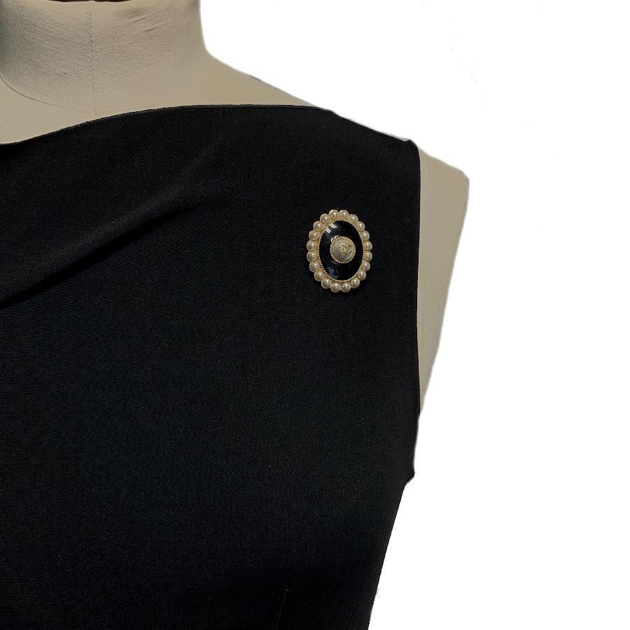 This Chanel brooch comes from the recent Paris Cuba 2017 cruise collection. Made in France.
It is oval, in black resin, gilded metal. It is set on all round with small pearl beads. There is a pearl in the middle on which is a golden CC.

In