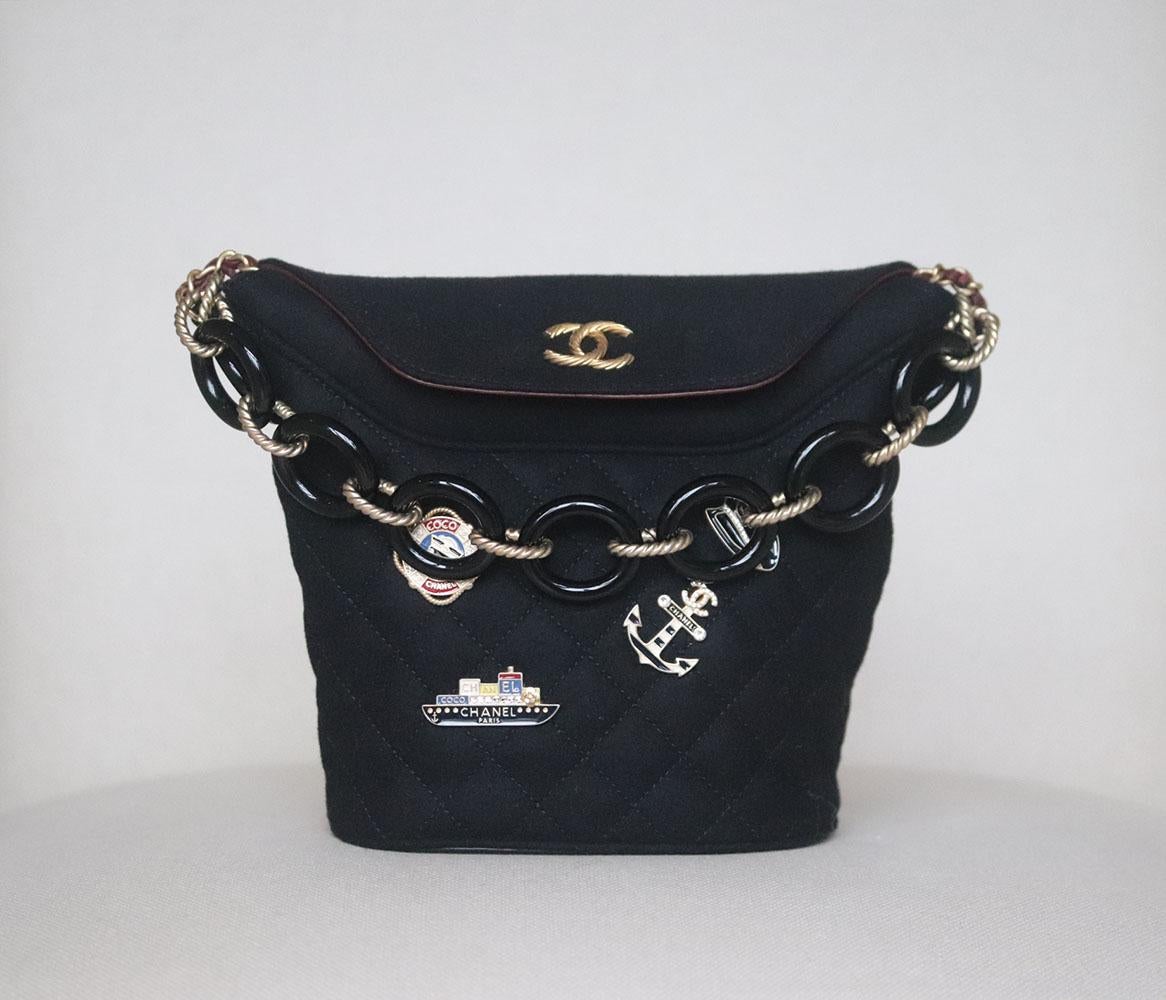 Chanel 2018 Paris-Hamburg Lambskin-Trimmed Quilted Wool Charm Bucket Bag has been hand-finished by skilled artisans in the label's workshop, it is boasting a beautiful charm embellished wool-felt exterior, this design is accented with gone-tone and