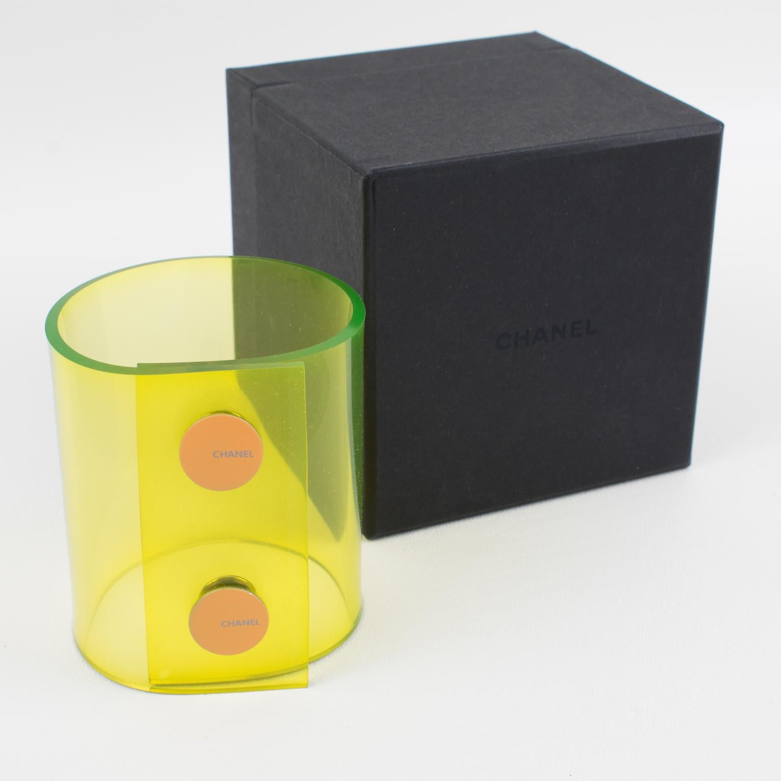 This elegant Chanel bracelet bangle features an oversized soft-plastic band with two snap buttons closing. The piece boasts a stunning transparent neon yellow color. The Chanel brand logo on the snap button reads © Chanel ® - 00 CC logo C - Made in