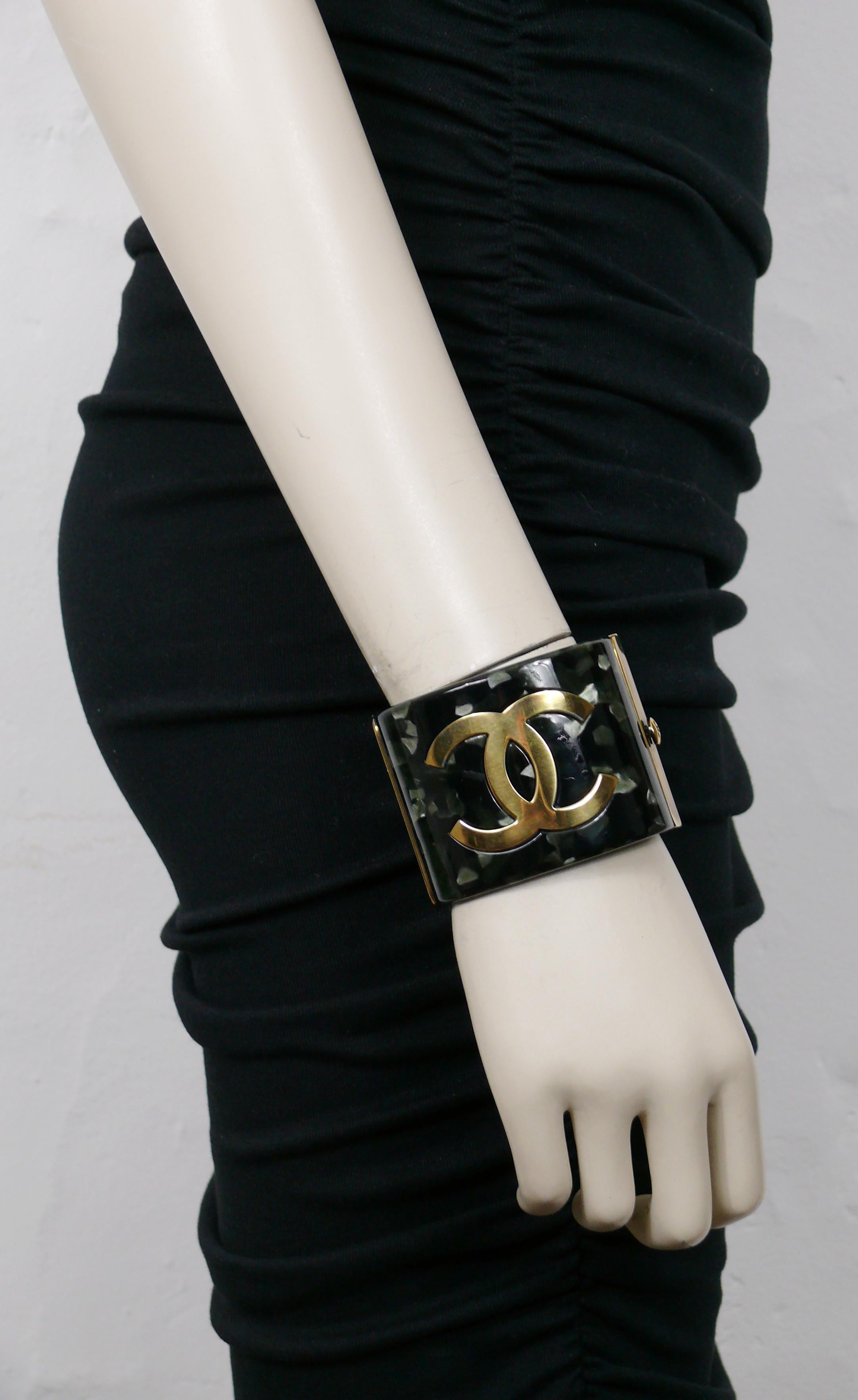 CHANEL by KARL LAGERFELD marbled dark green resin cuff bracelet featuring a large CC logo on one side and chinese ideograms on the other side.

Oxidized gold tone metal hardware.

From the Pre-Fall 2010 Metiers D'Art Paris-Shanghai Collection.

Push