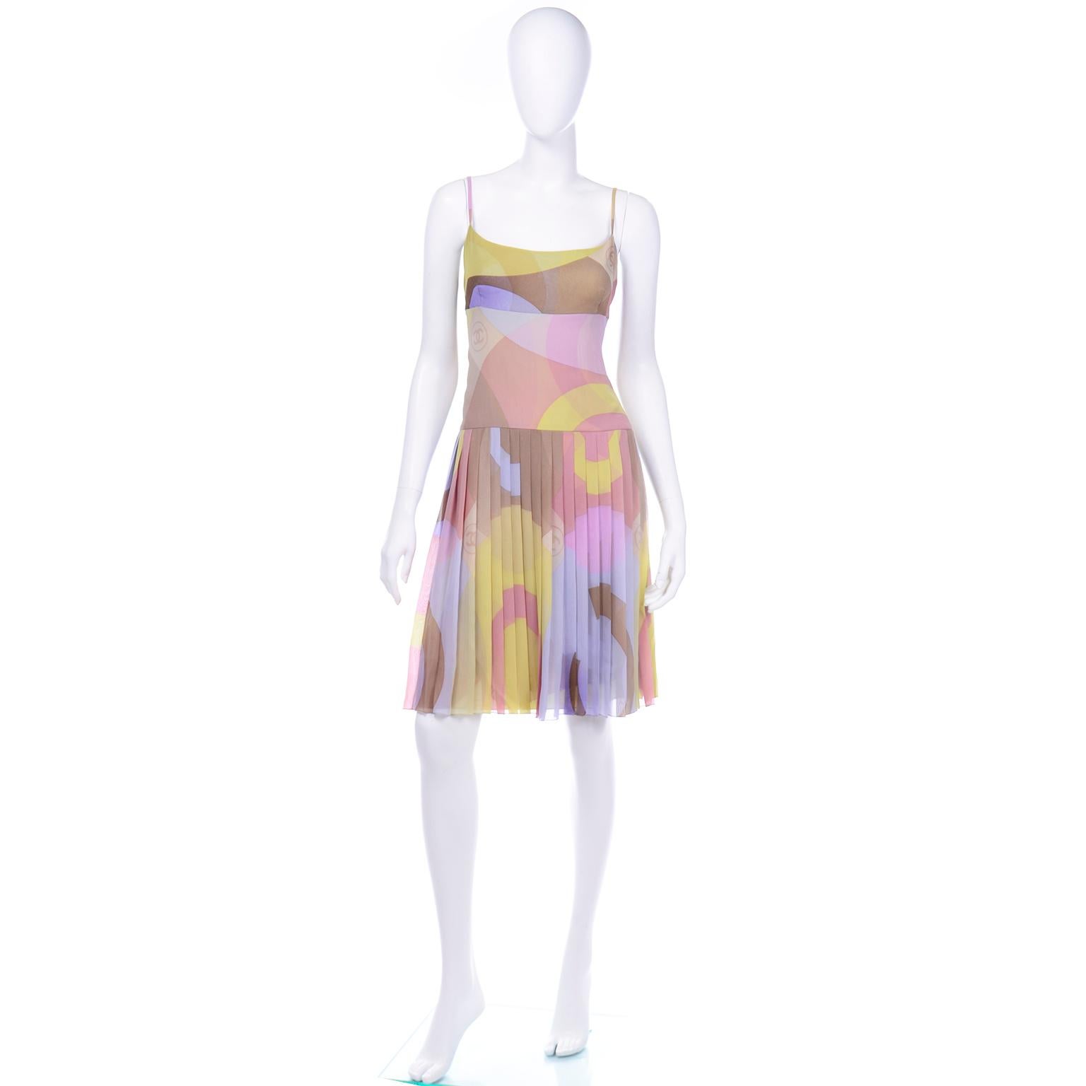 We think this is the perfect Spring Summer dress! This Chanel 2001 Cruise collection dress is in a beautiful silk abstract logo print in soft muted shades of lime green, light brown, lavender, periwinkle, tan, mauve, pink, and yellow. The Chanel