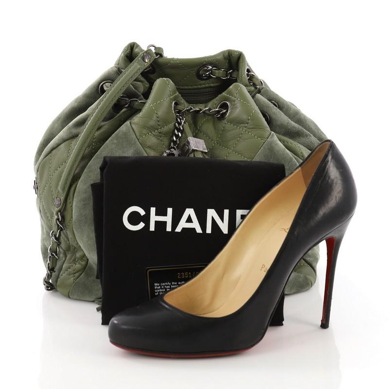This Chanel Patchwork Drawstring Bag Quilted Leather and Suede Small, crafted from green quilted leather and suede, features dual woven-in leather chain straps with leather pads, logo charm and tassel embellishments at front, and aged silver-tone
