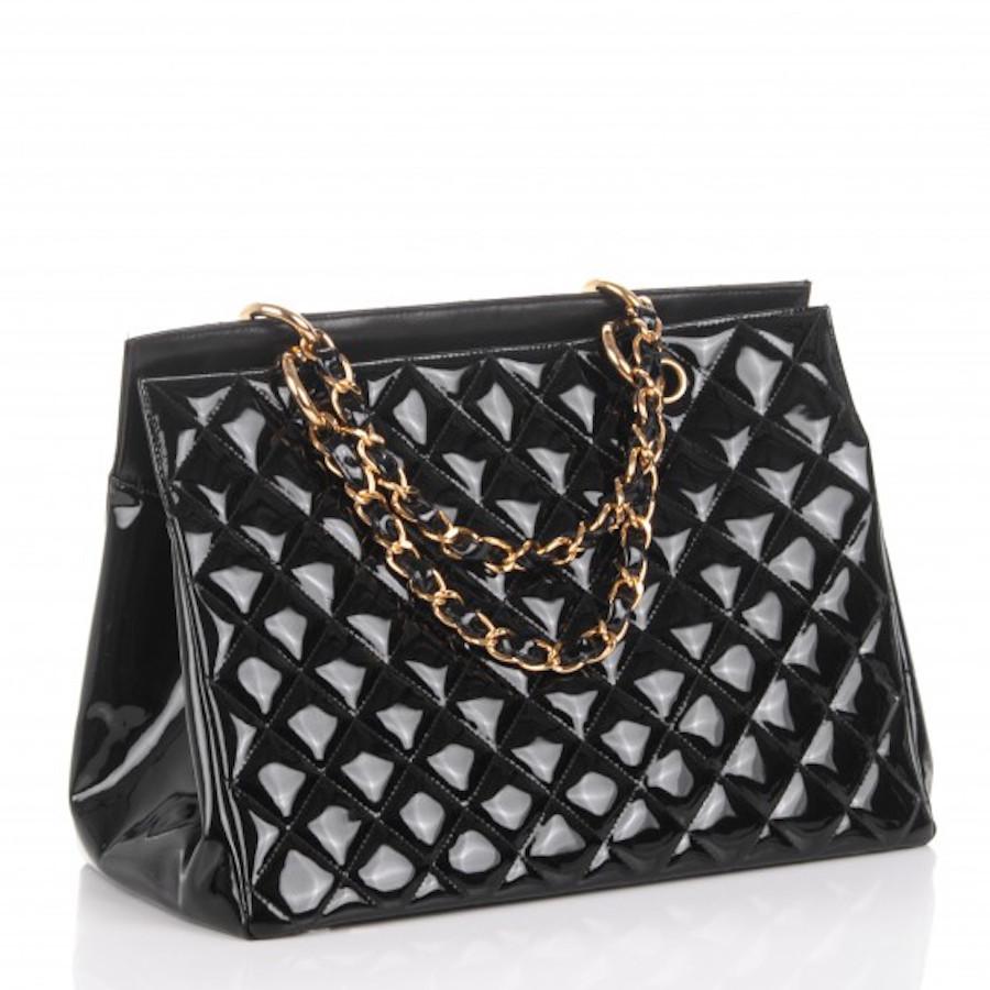  This stunning tote is beautifully crafted of luxurious diamond quilted black shiny patent leather. The bag features shoulder straps with gold chain links threaded as well as a prominent frontal stitched Chanel CC logo and a rear pocket. The top