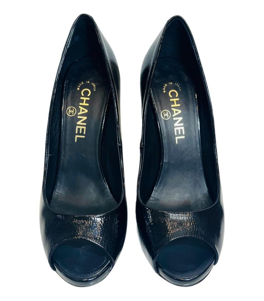 Chanel Patent Leather 'CC' Logo Heels With Pearl Detail
Navy peep-toe heels designed with stiletto heel detailed with pearl.
Featuring gold 'CC' logo accent to the side and leather lining.
Size – 38.5
Condition – Good (Scratches to the