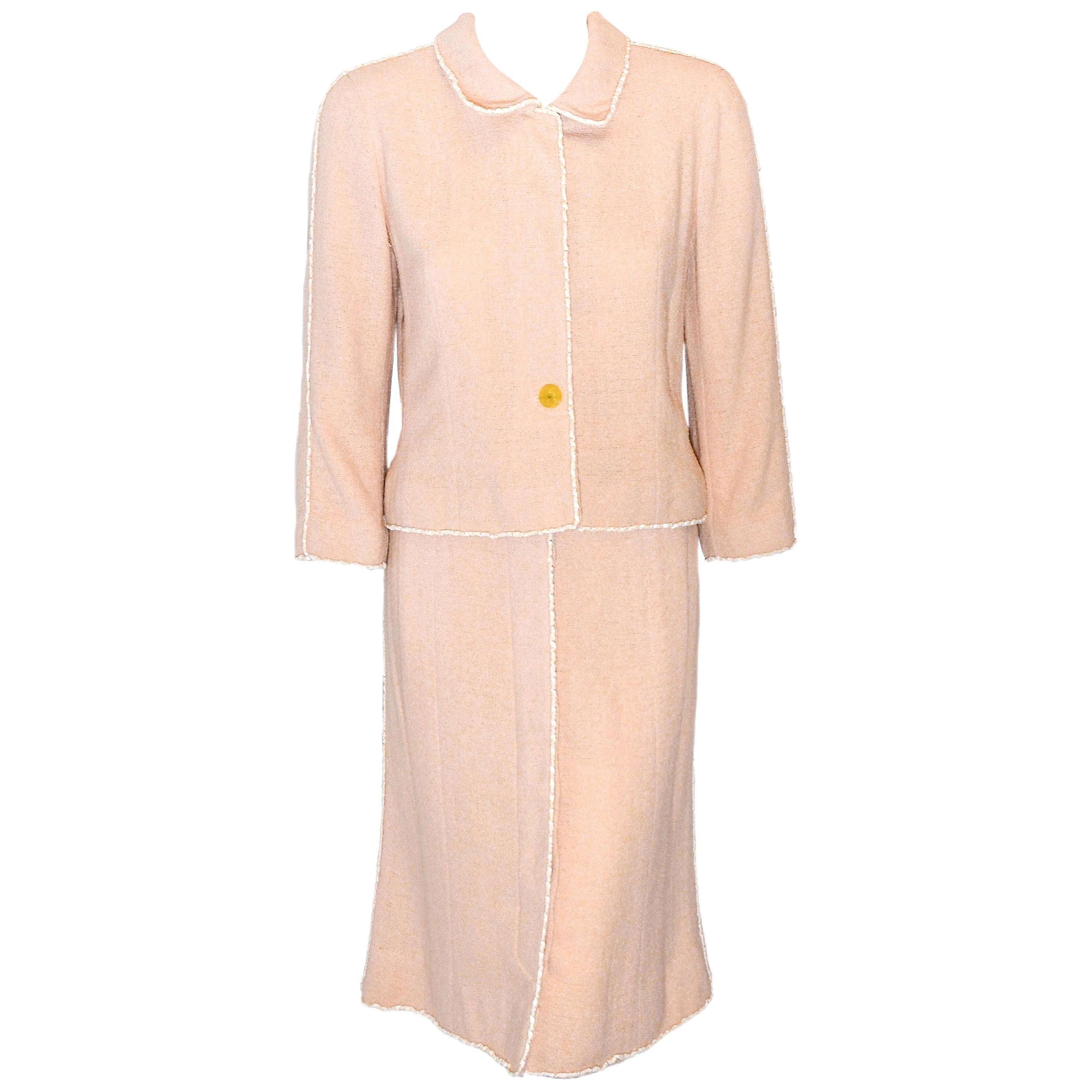 Chanel peach wool blend skirt suit with white trim is lined in Chanel logo peach silk.  The Jacket includes 4 CC hidden buttons and one exposed button and the skirt contains 6 hidden buttons and 2 exposed buttons at the waist.  Both the jacket and