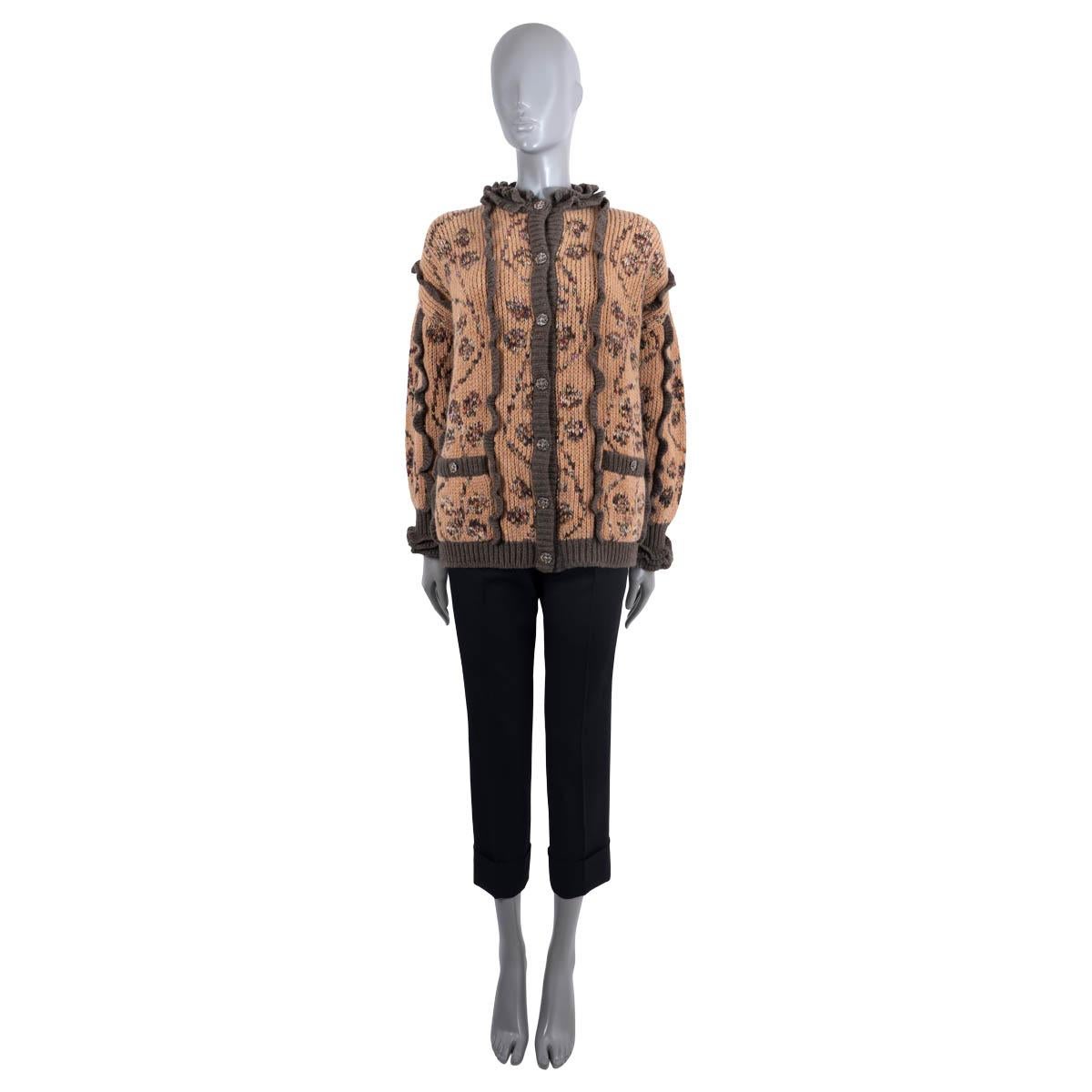 100% authentic Chanel knit jacket in peachy brown cashmere (65%) and wool (35%). Featuring contrast dark brown trim, multicolor floral intarsia, ruffled neck and cuffs and two buttoned pockets at the waist. Closes with multicolor rhinestone