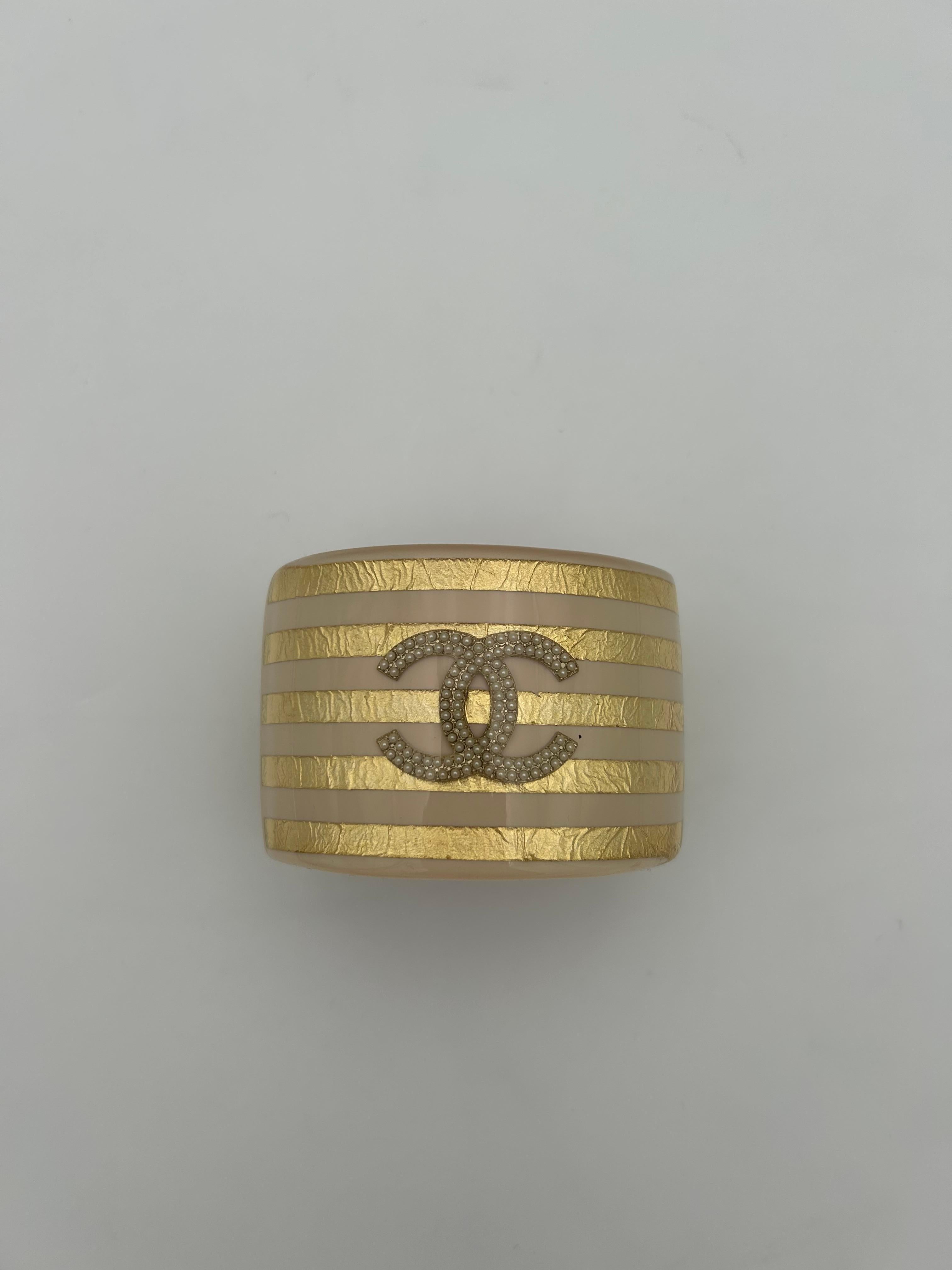 Bracelet manchette Chanel en perles et beige. Ce magnifique bracelet manchette est une pièce d'apparat parfaite à ajouter à votre collection. La couleur n'est pas trop vive ou audacieuse, mais plutôt classe et simple, ce qui en fait une pièce très