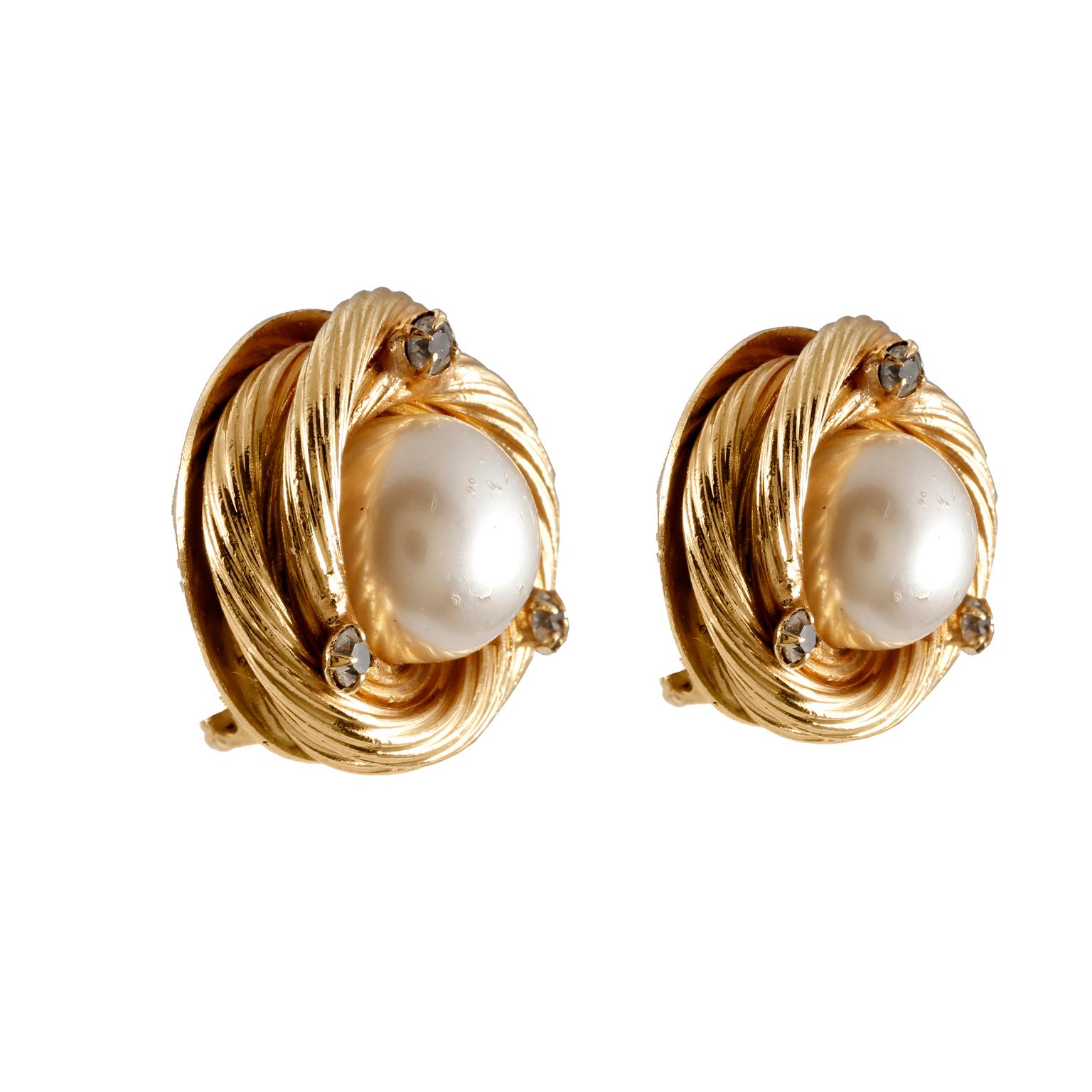 These authentic Chanel Pearl and Crystal Gold Knot Earrings are in very good condition from the Spring 1993 collection.  Large faux pearls are centered within a swirling gold tone surround.  Three small crystals embellish each earring.  Clip on