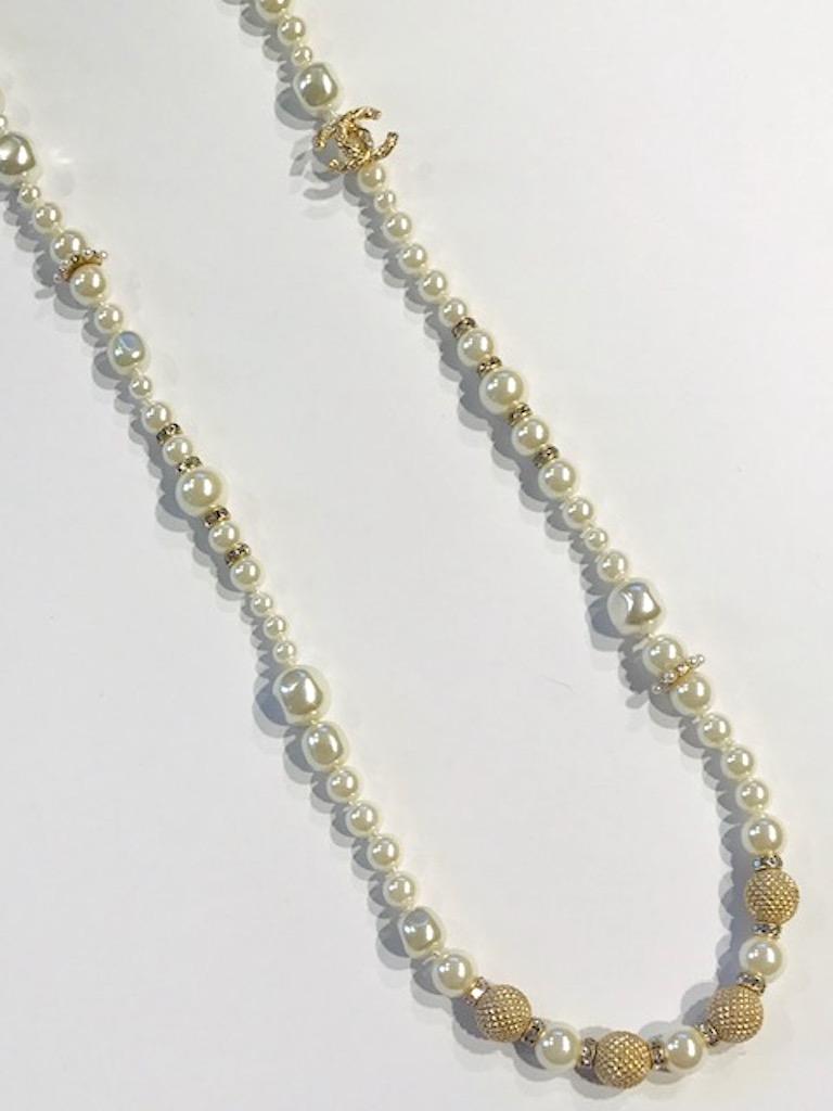 A Chanel very elegant single strand of round and Baroque faux pearls, rhinestone rondel, and gold bead long necklace. The individually knotted pearls vary in size from 5 to 12 mm. The Baroque style are the largest. The pearls are offset with the use