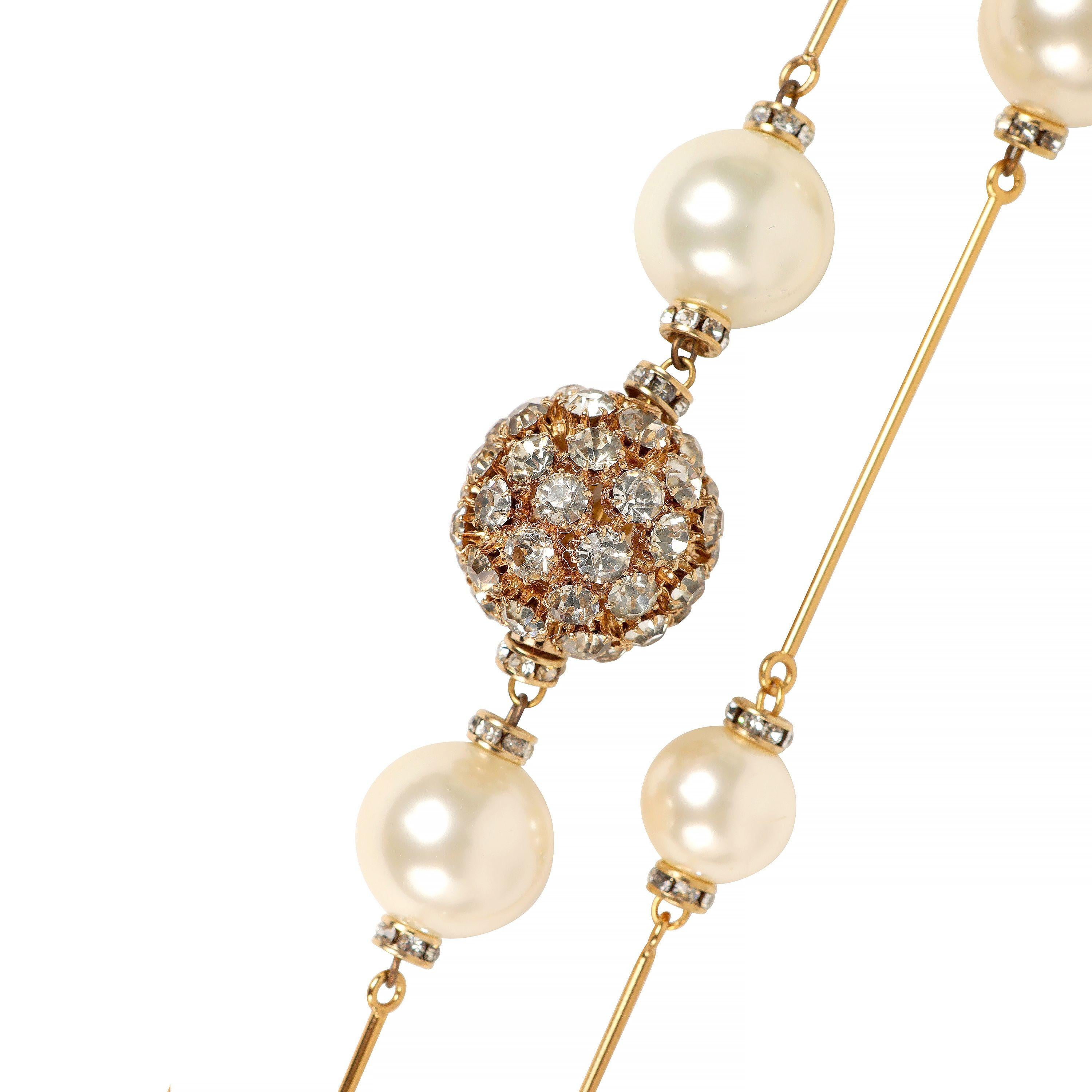 This authentic Chanel Pearl and Gold Pin Extra Long Necklace is in pristine condition.  Worn single or double.  Large faux pearls connected with gold tone “pins” and interspersed with crystals and an amber crystal ball.  Pouch or box included.


