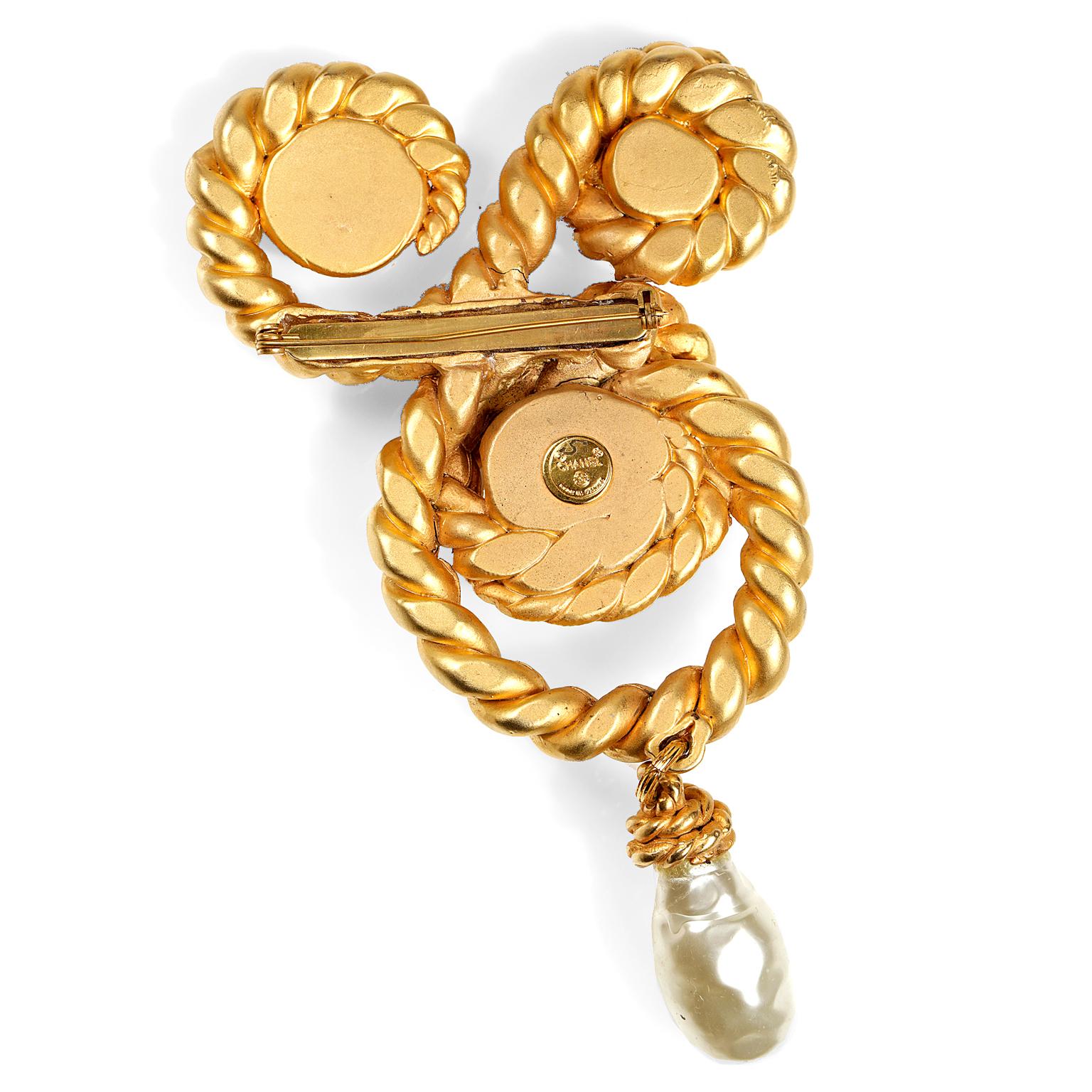 Chanel Pearl and Gold Rope Pin- mint condition; Circa 1980’s, designed by Karl Lagerfeld.
 Matte gold swirling rope cradles three faux pearls.  A single baroque pearl dangles from the bottom.  Made in France. 
Measurements:  7”

