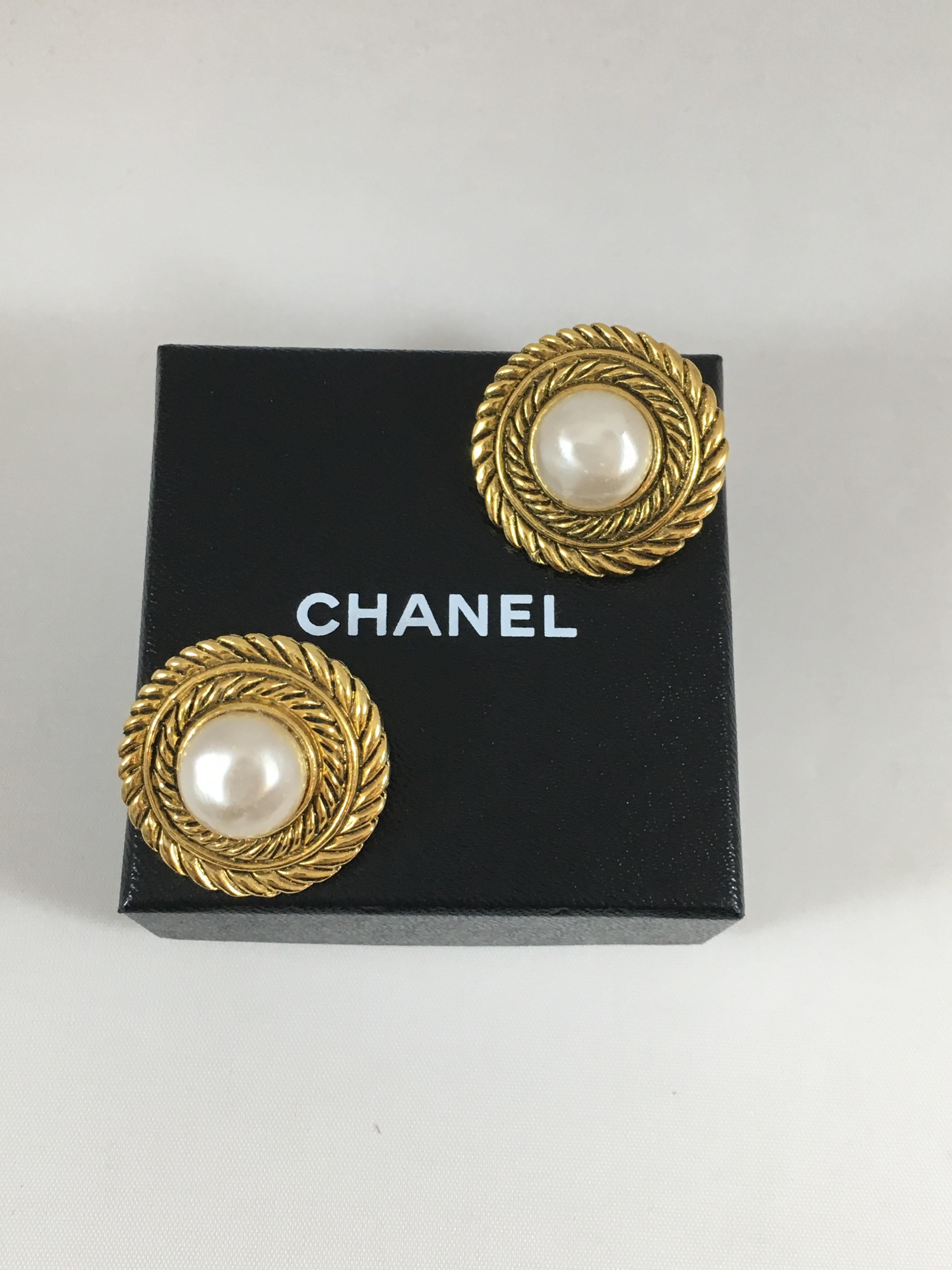 This is a fabulous pair of 1980s Chanel earrings in their original box. They are goldtone clip on earrings and feature a large round faux pearl in the center. They are beautifully made and are in excellent condition. They measure 1 1/8 inches in