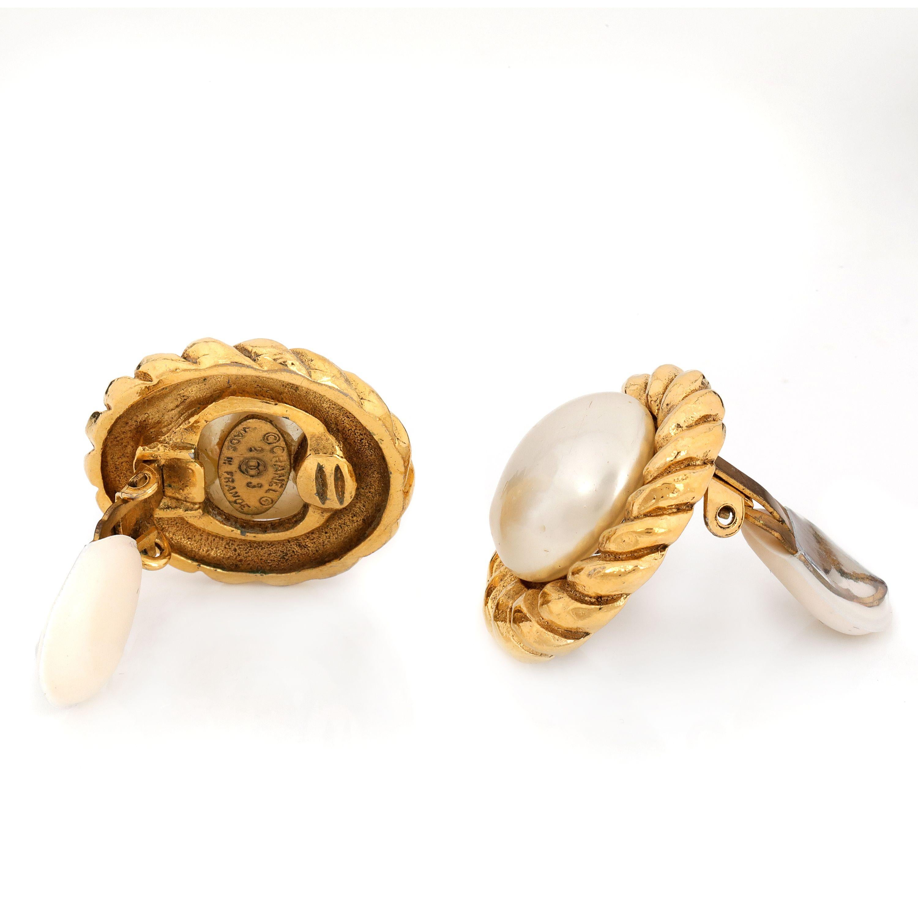 These authentic Chanel Pearl Button Gold Rope Clip On Earrings are in excellent vintage condition from the 1980’s.  Large faux pearl centers are surrounded with gold tone rope design.  Clip on style.  Made in France. Pouch or box included.  

PBF