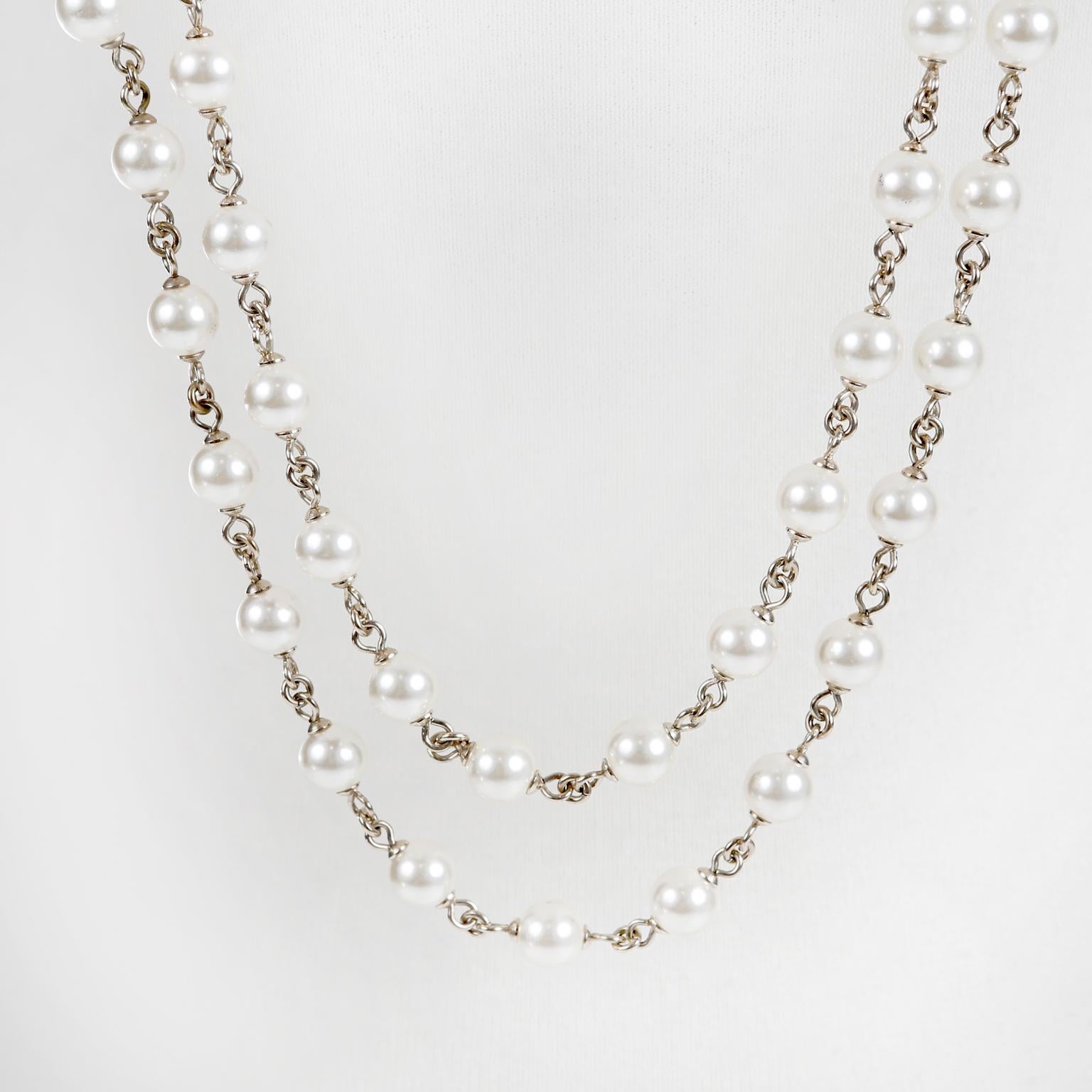 This authentic Chanel Pearl Double Strand CC Necklace is in excellent condition.  Round faux pearls are stationed along a silver tone chain with green stone and interlocking CC embellishment.   

