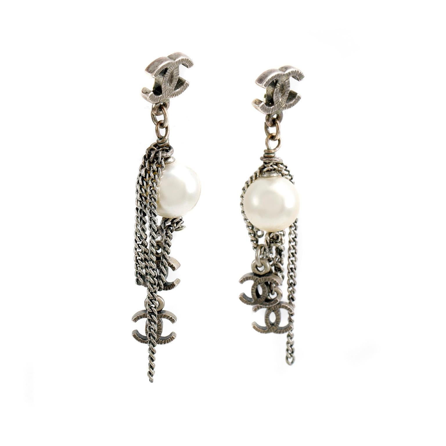 These authentic Chanel Pearl Dripping Chains CC Earrings are in pristine condition.   A faux round pearl and silver chains dangle from a silver interlocking CC.  Smaller silver interlocking CC charms at the base of the chains add even more glamor to