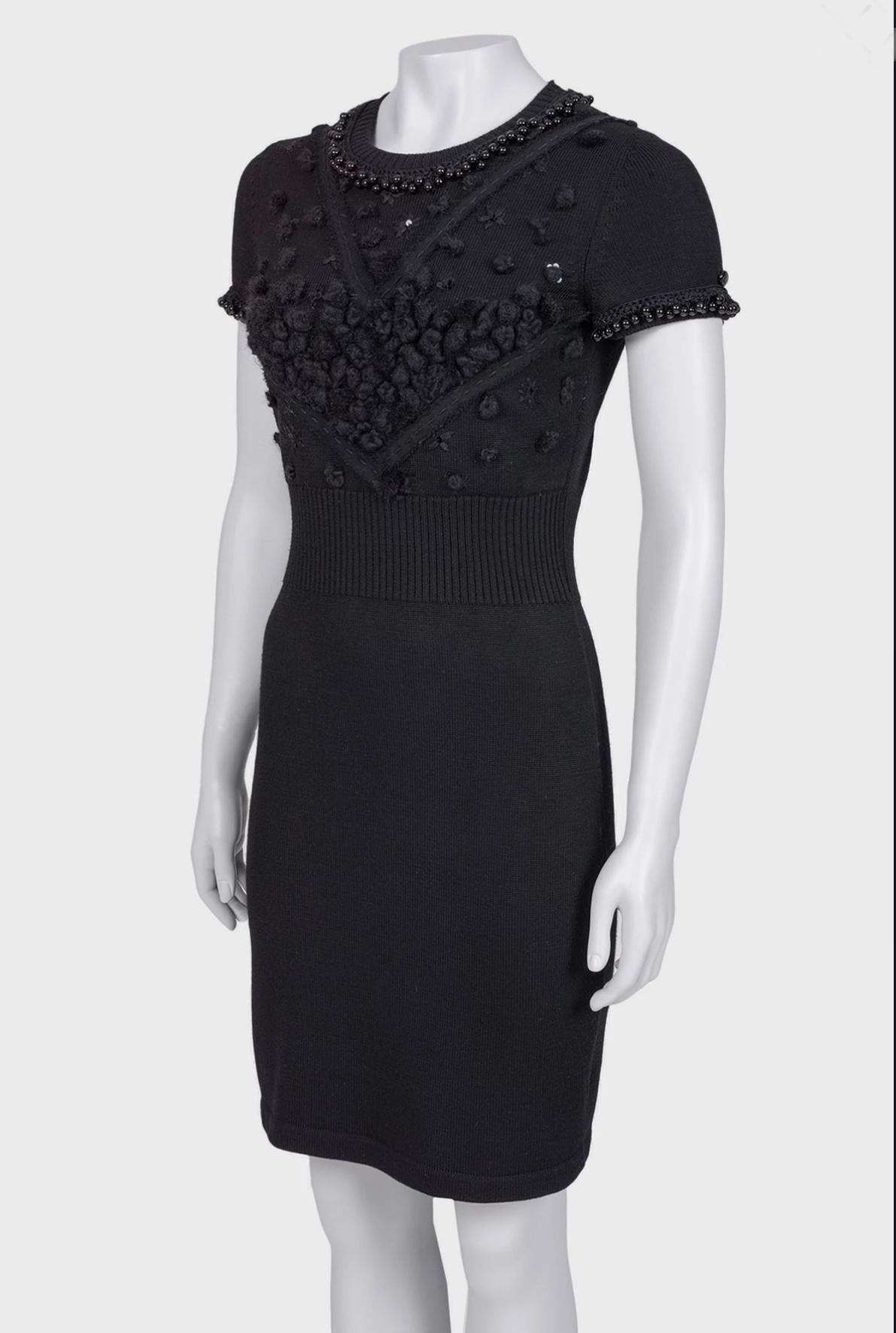 Chanel black knit dress with pearl embellishment and couture applique at chest.
- CC logo charm at sleeve
Size mark 40 FR. Pristine condition.
