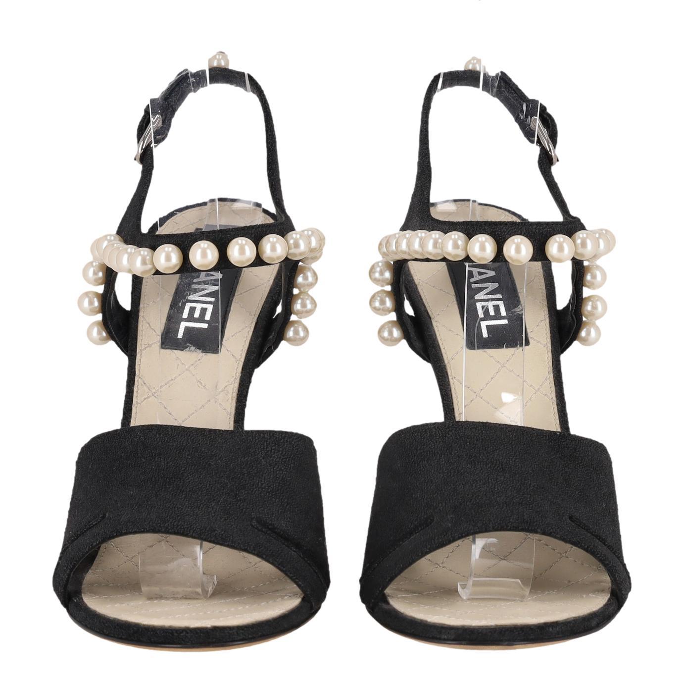Sandales en daim ornées de perles de Chanel

Talons en daim noir conçus avec une large bride, détaillés avec des découpes sur les côtés.

Whiting, la bride cheville est ornée de perles blanches et se ferme à l'aide d'une boucle.

Il est orné au dos