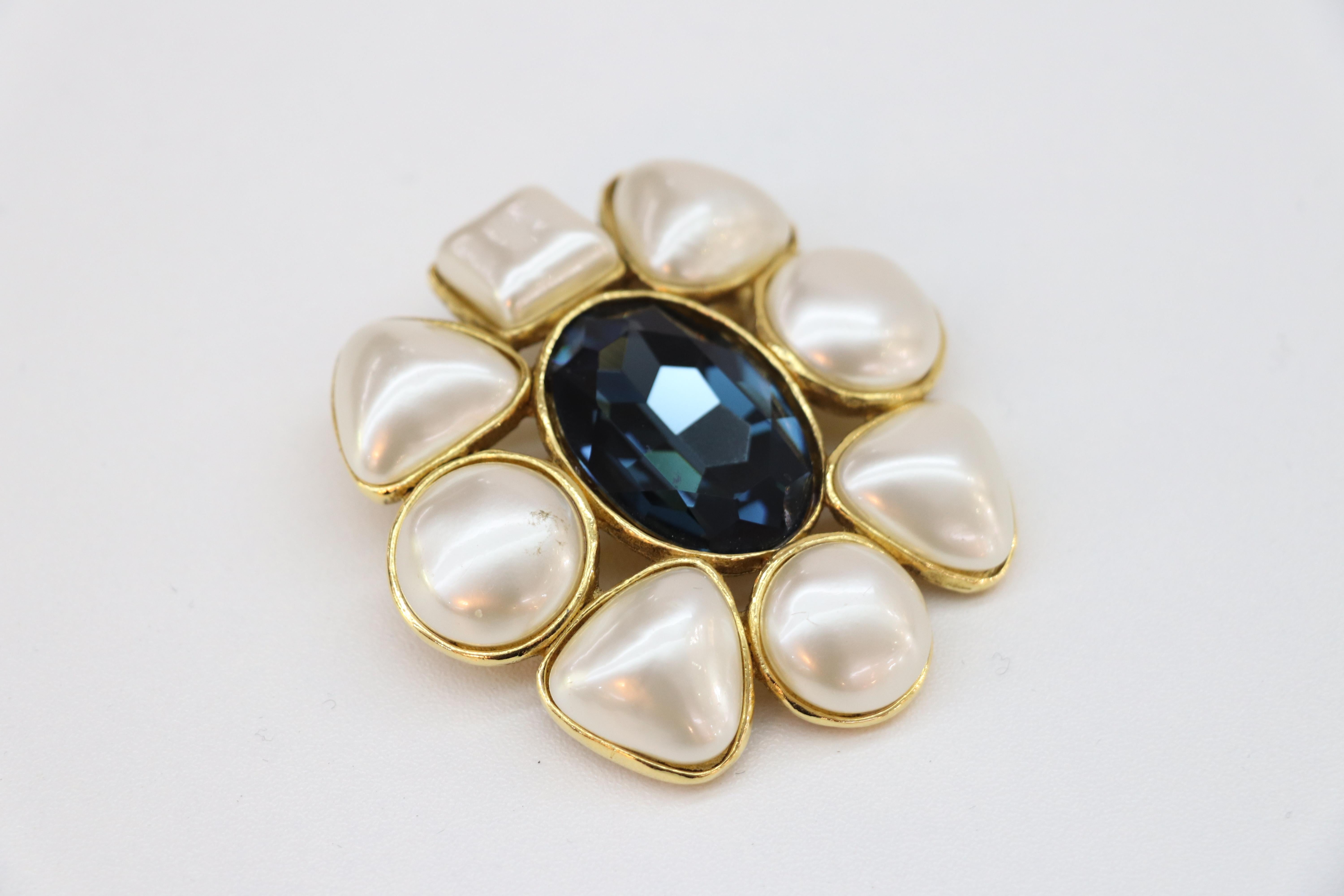 Chanel vintage flower brooch, dating to the 1980's, showcases 24k gold plating with eight faux pearls in varying shapes and sizes, with a blue oval center stone. This stunning piece has a secure lock pin backing and looks fabulous on any blazer or